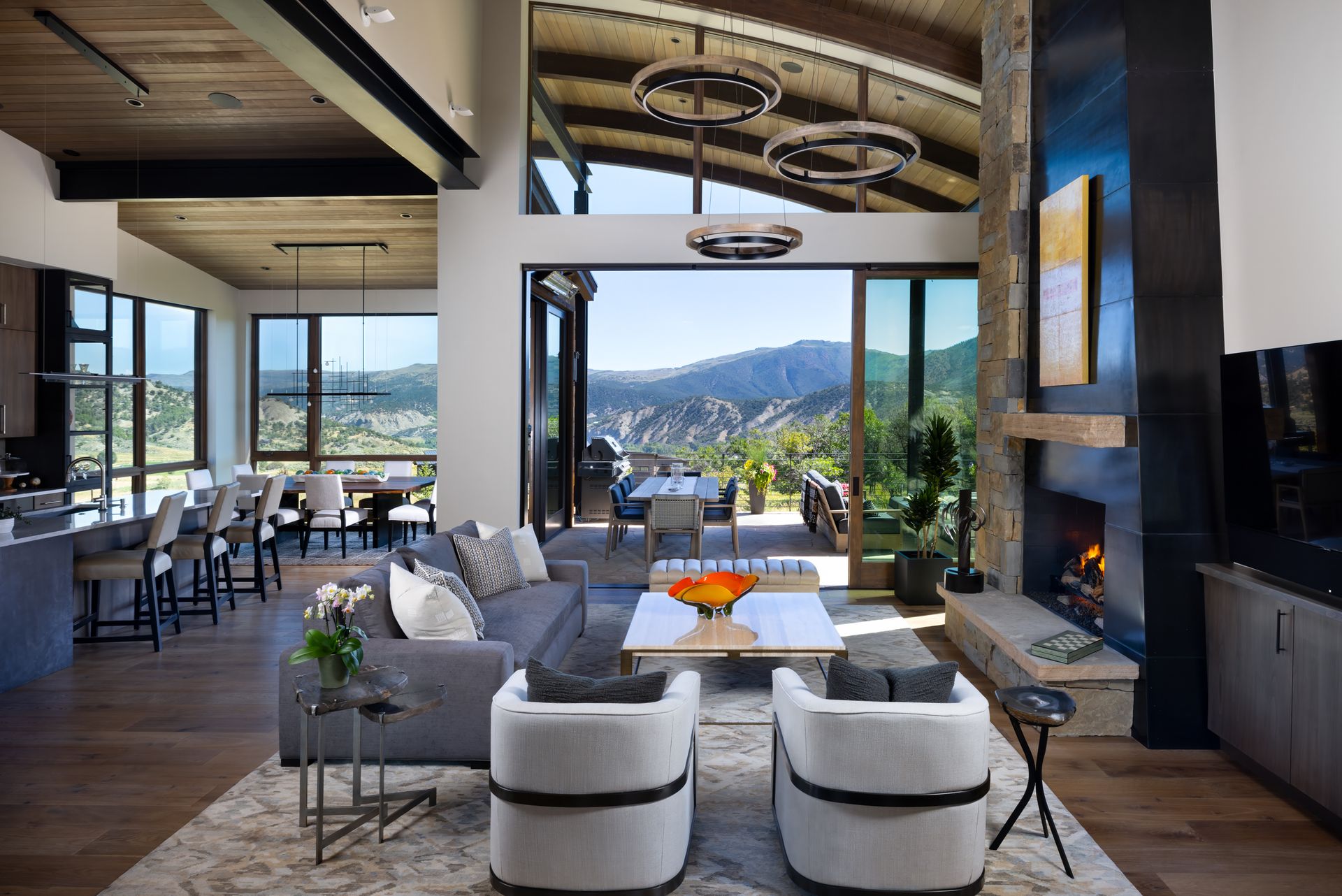 A living room with a couch , chairs and a fireplace with a view of the mountains.