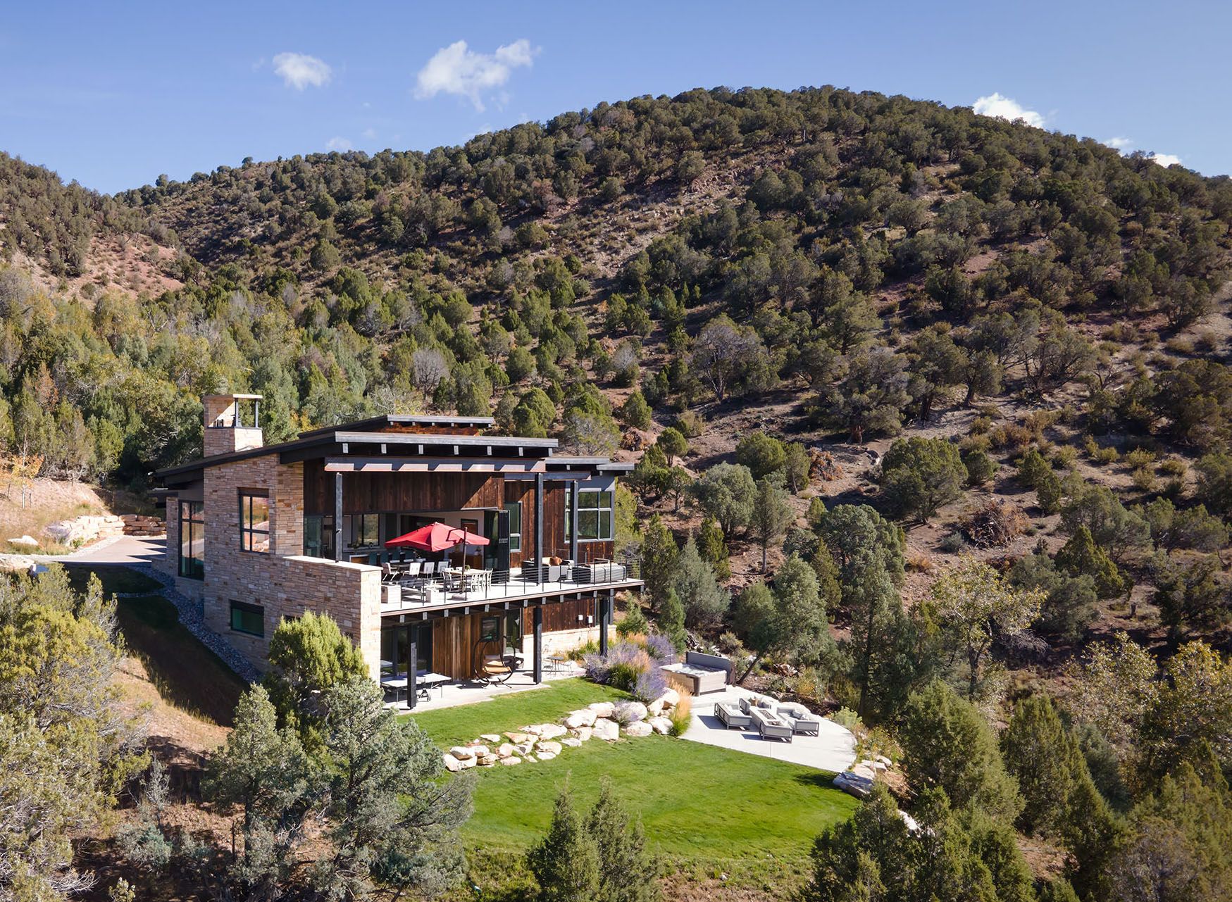 A large house sits on top of a hill surrounded by trees