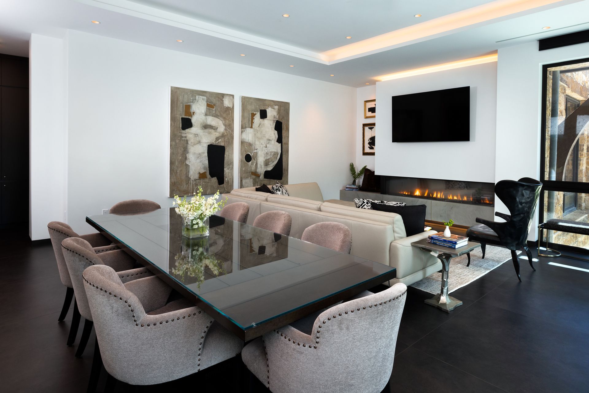 A living room with a dining table and chairs and a flat screen tv.