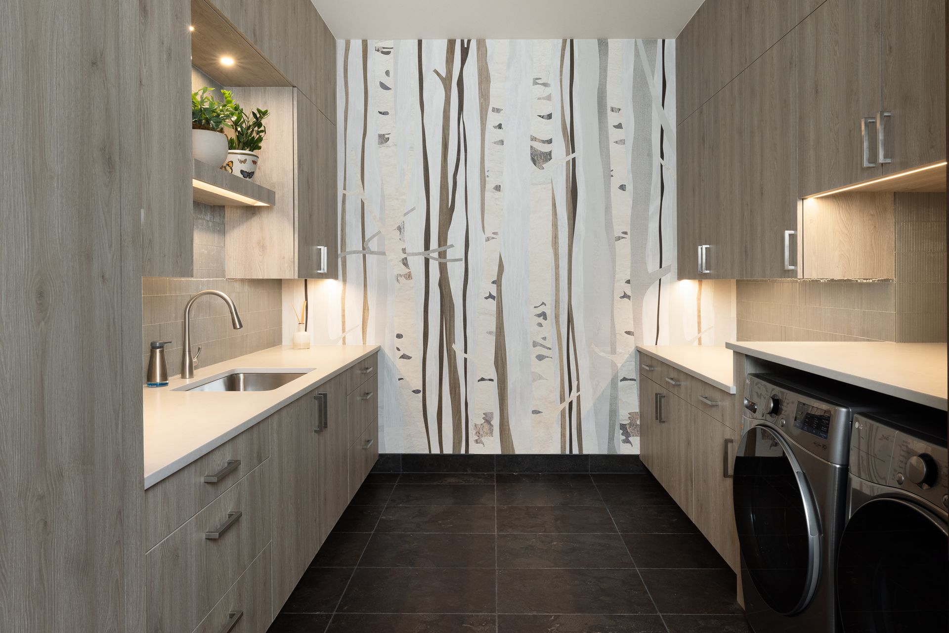 A laundry room with a washing machine , sink , and cabinets.