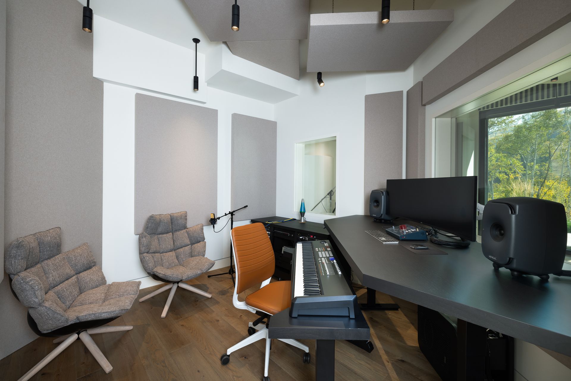 A recording studio with a keyboard and a computer on the desk.