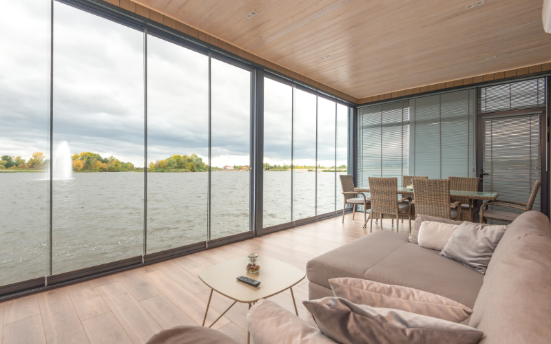 A living room with a lot of windows overlooking a lake.