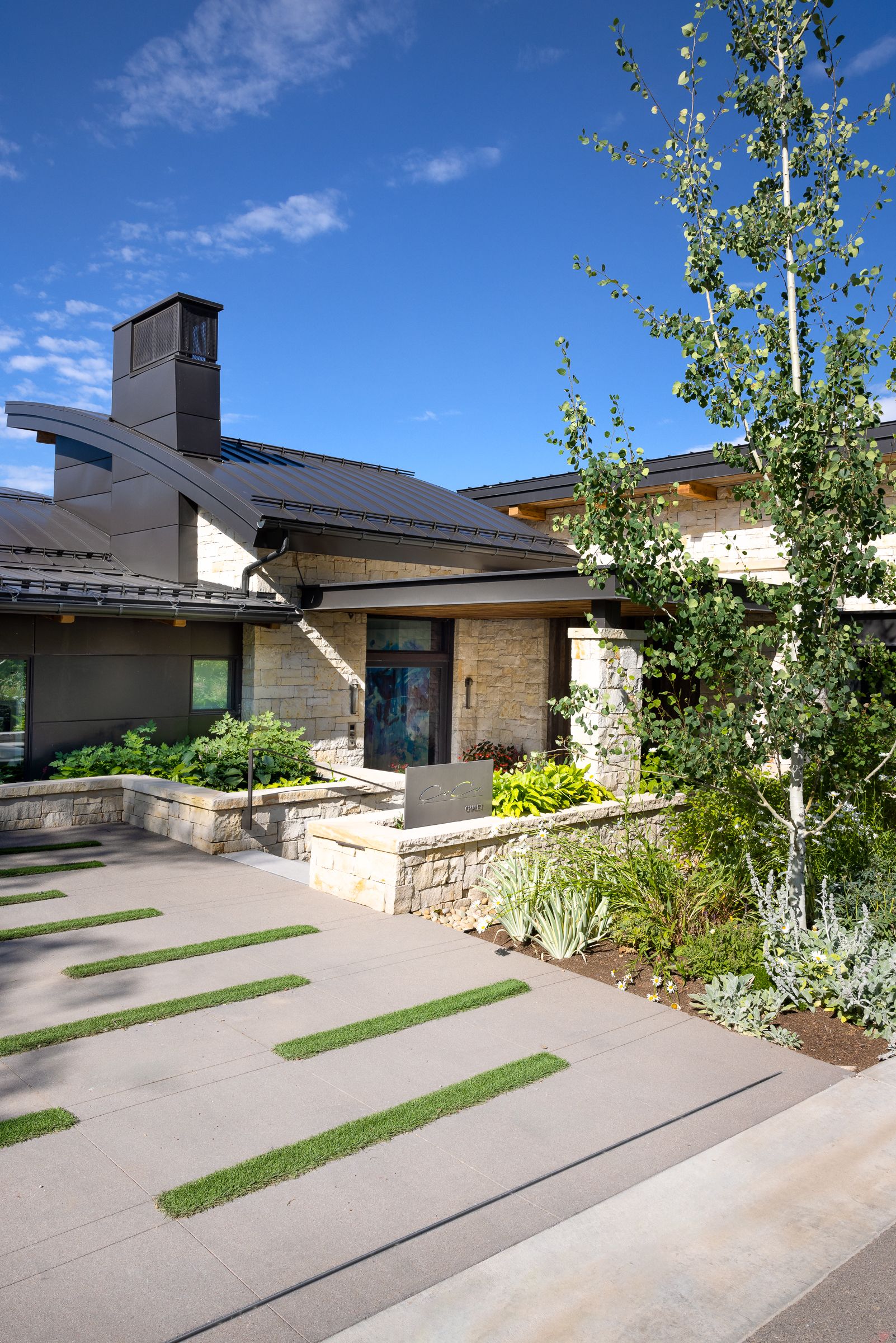 A large house with a concrete driveway and a stone wall