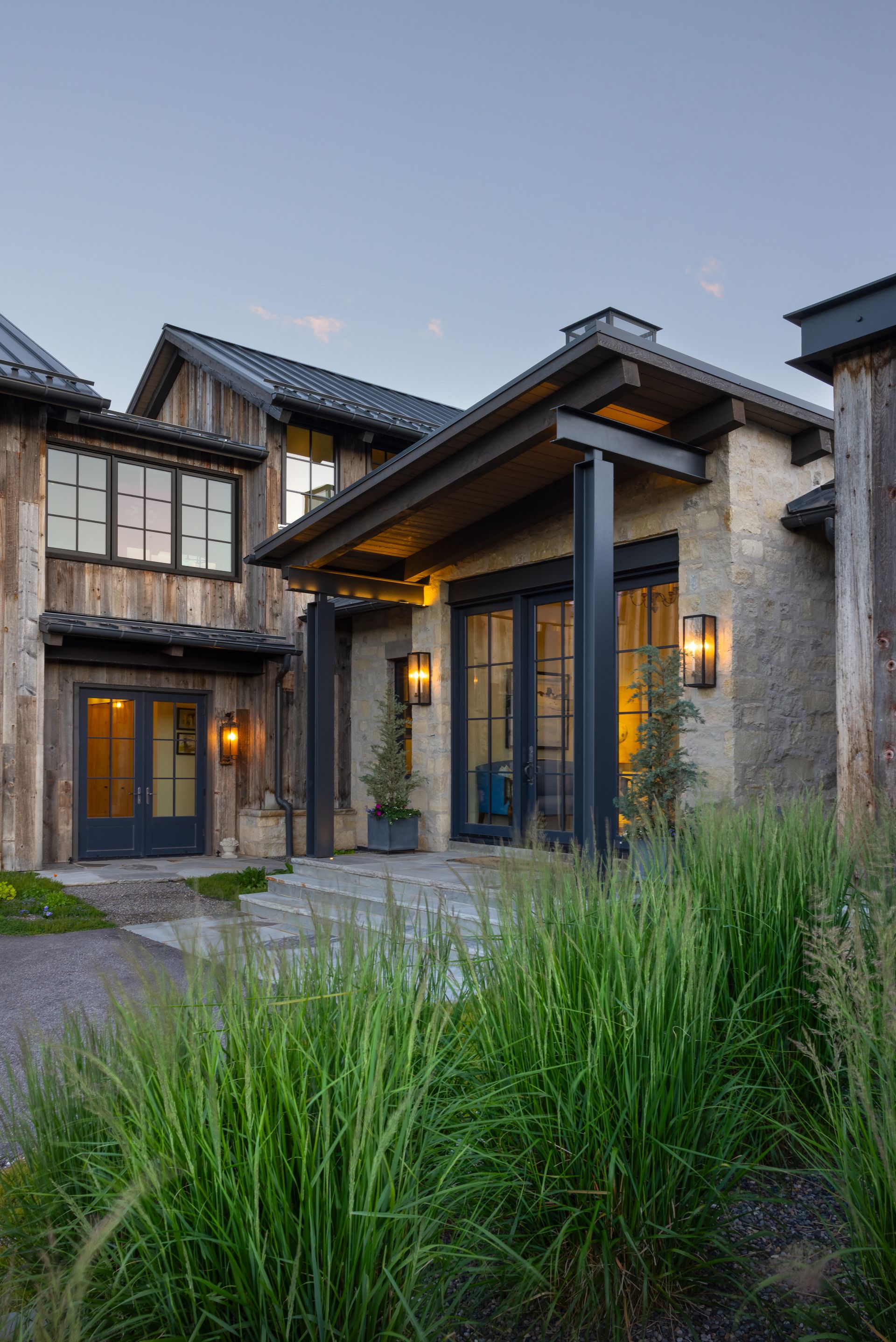 A large house with a lot of windows and a porch surrounded by tall grass.