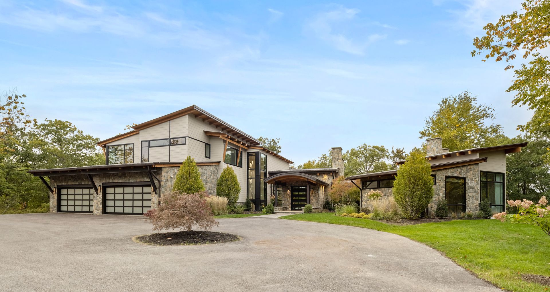 A large house with a driveway and a tree in front of it.