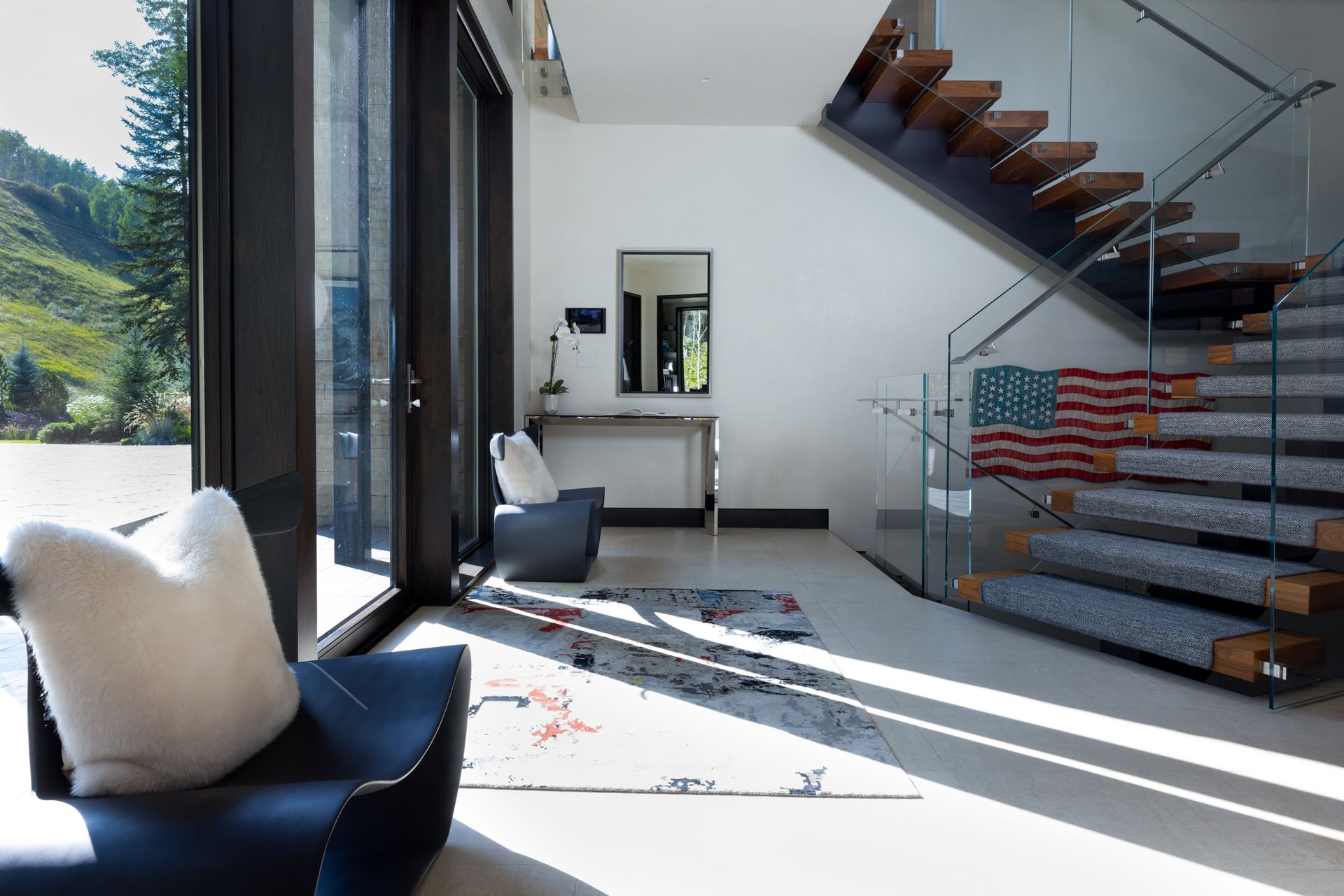 A living room with a staircase and an american flag on the floor