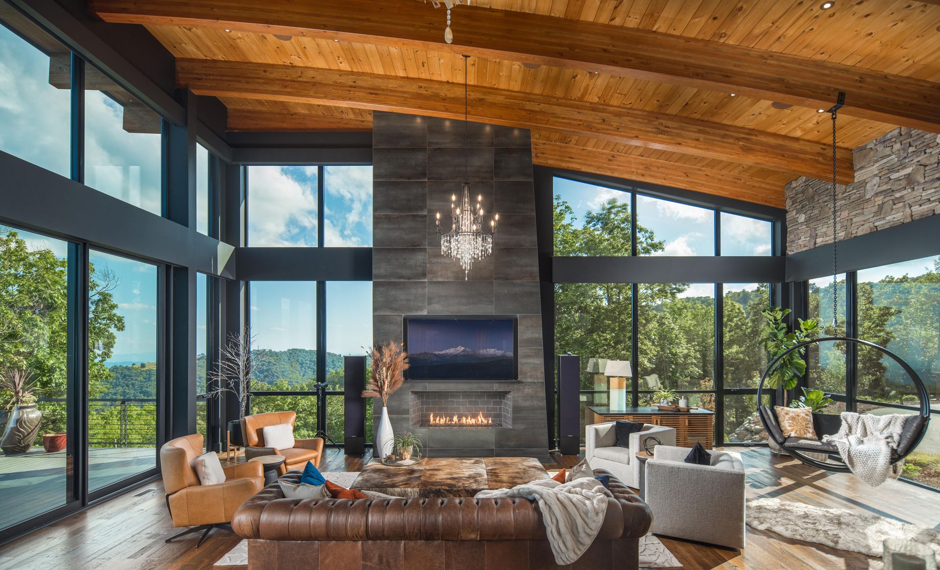 A living room with a couch , chairs , television and fireplace.