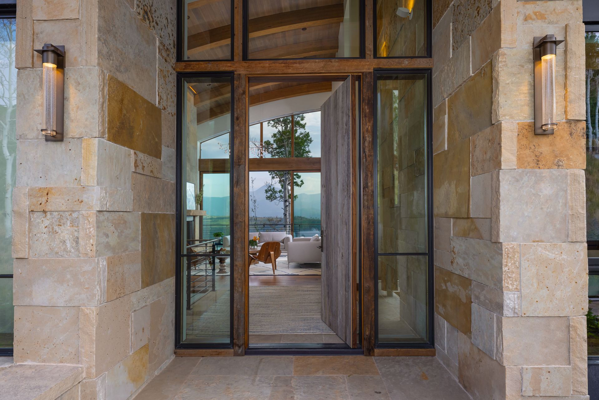 The front door of a house with a lot of windows and a wooden door.