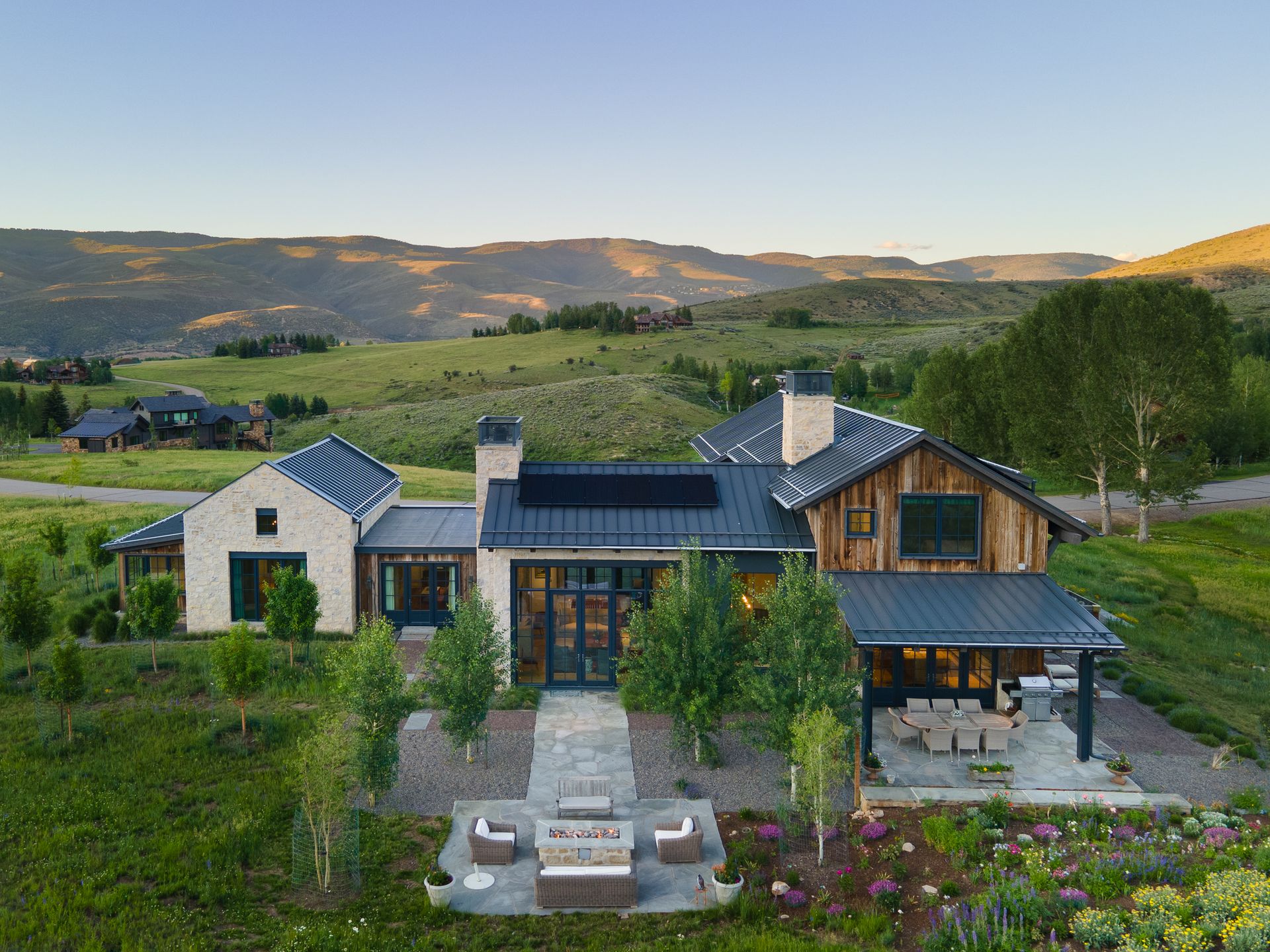 An aerial view of a house in the middle of a field with mountains in the background.