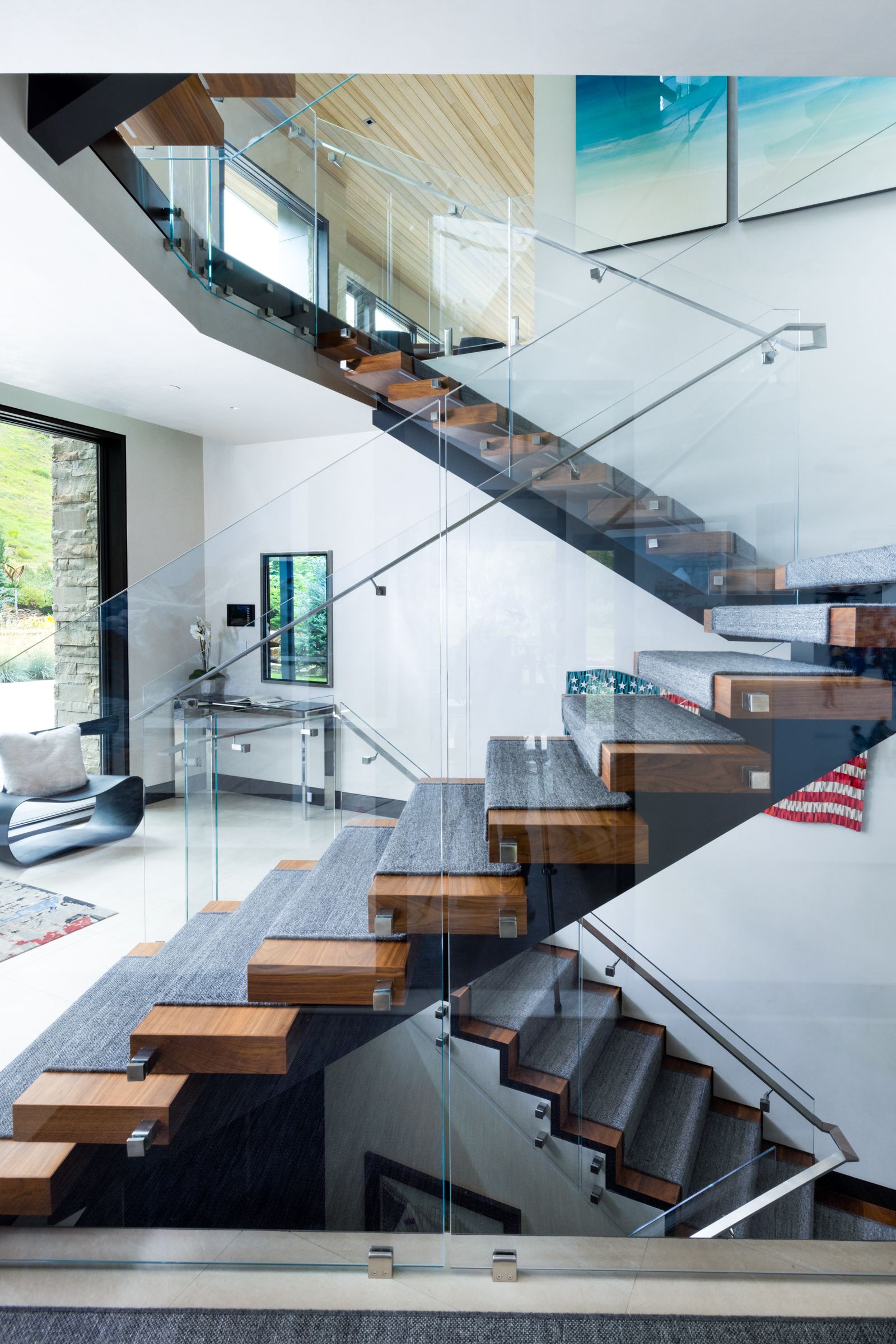 A modern staircase with a glass railing and wooden steps