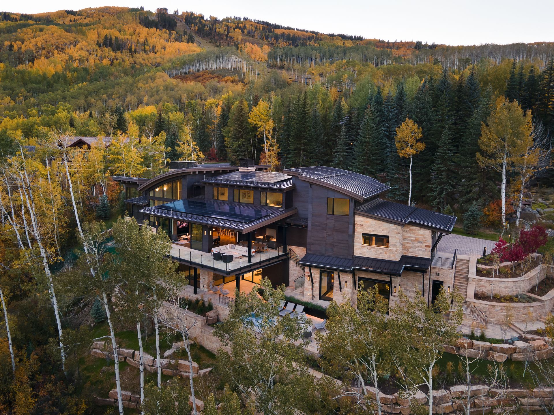 An aerial view of a large house in the middle of a forest.