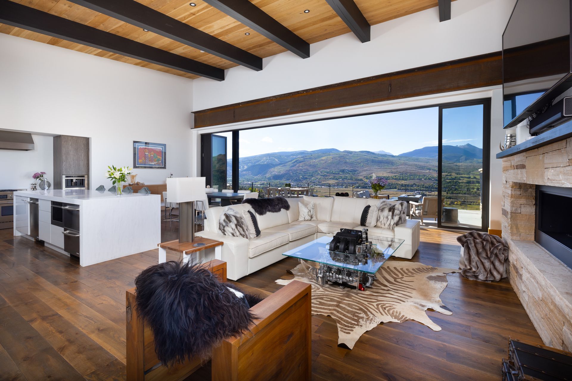 A living room with a couch , chairs , and a fireplace with a view of the mountains.
