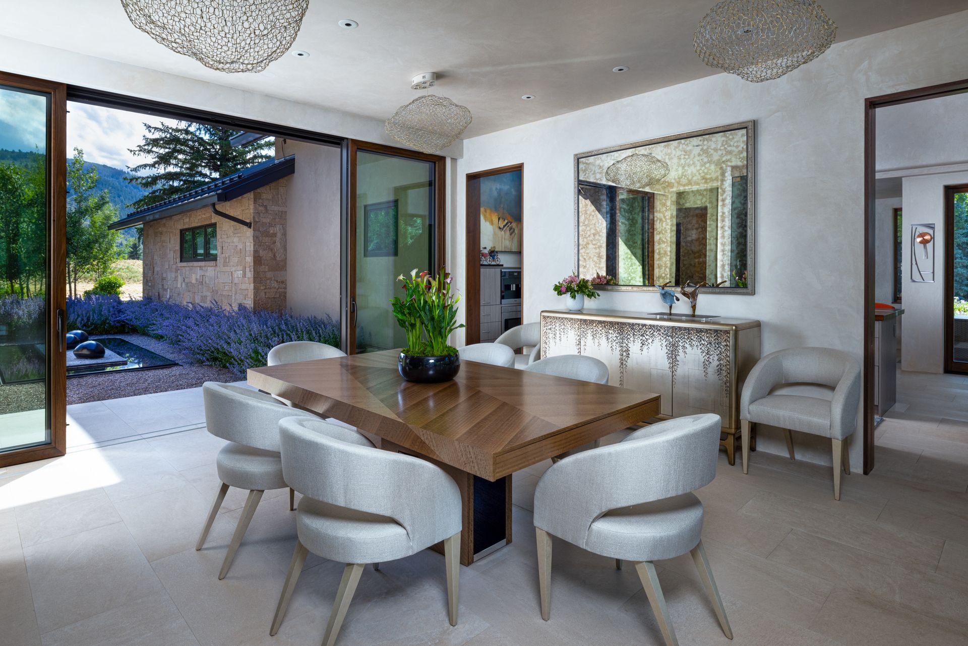 A dining room with a wooden table and white chairs.