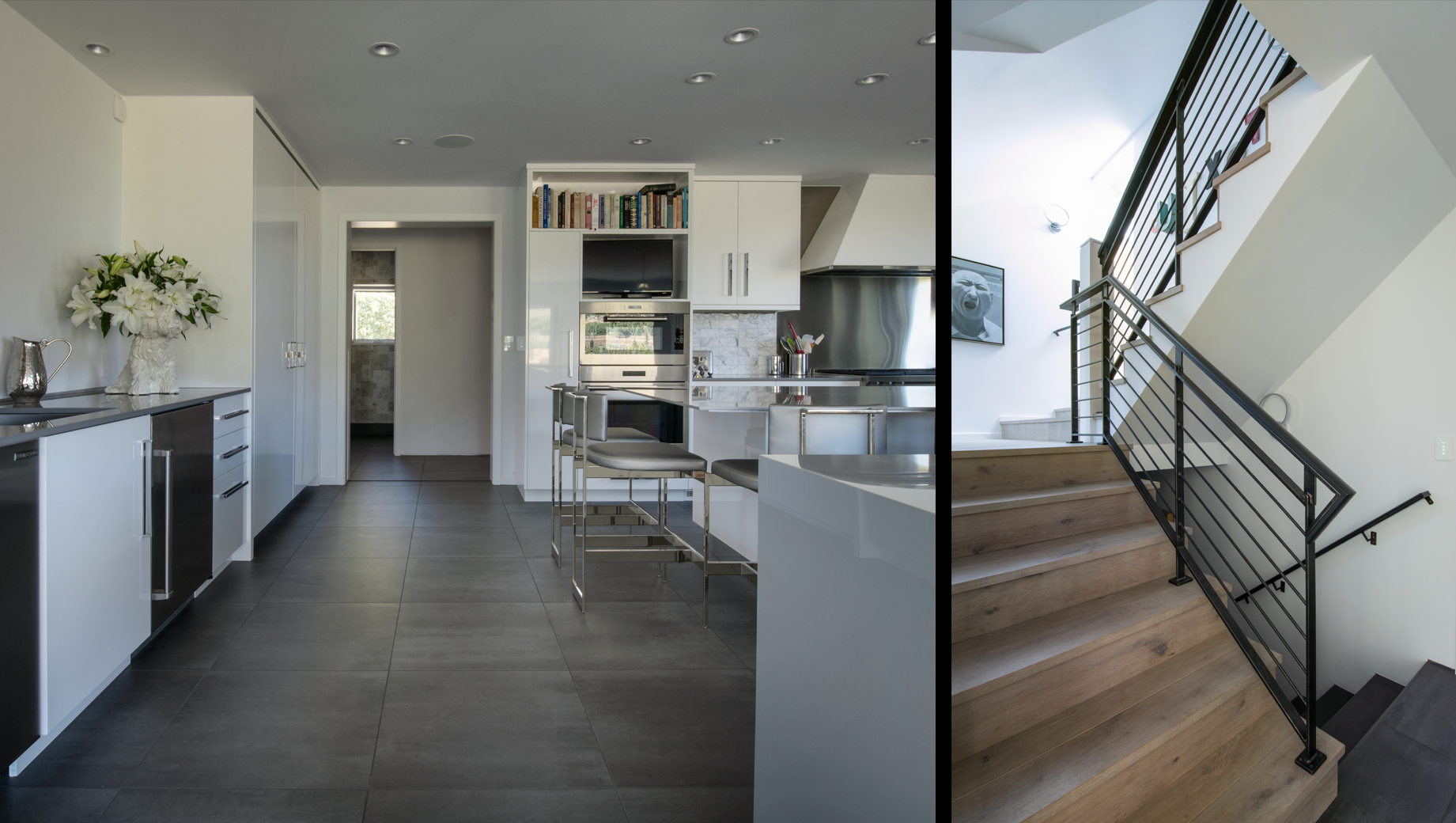 A kitchen and stairs with a black railing