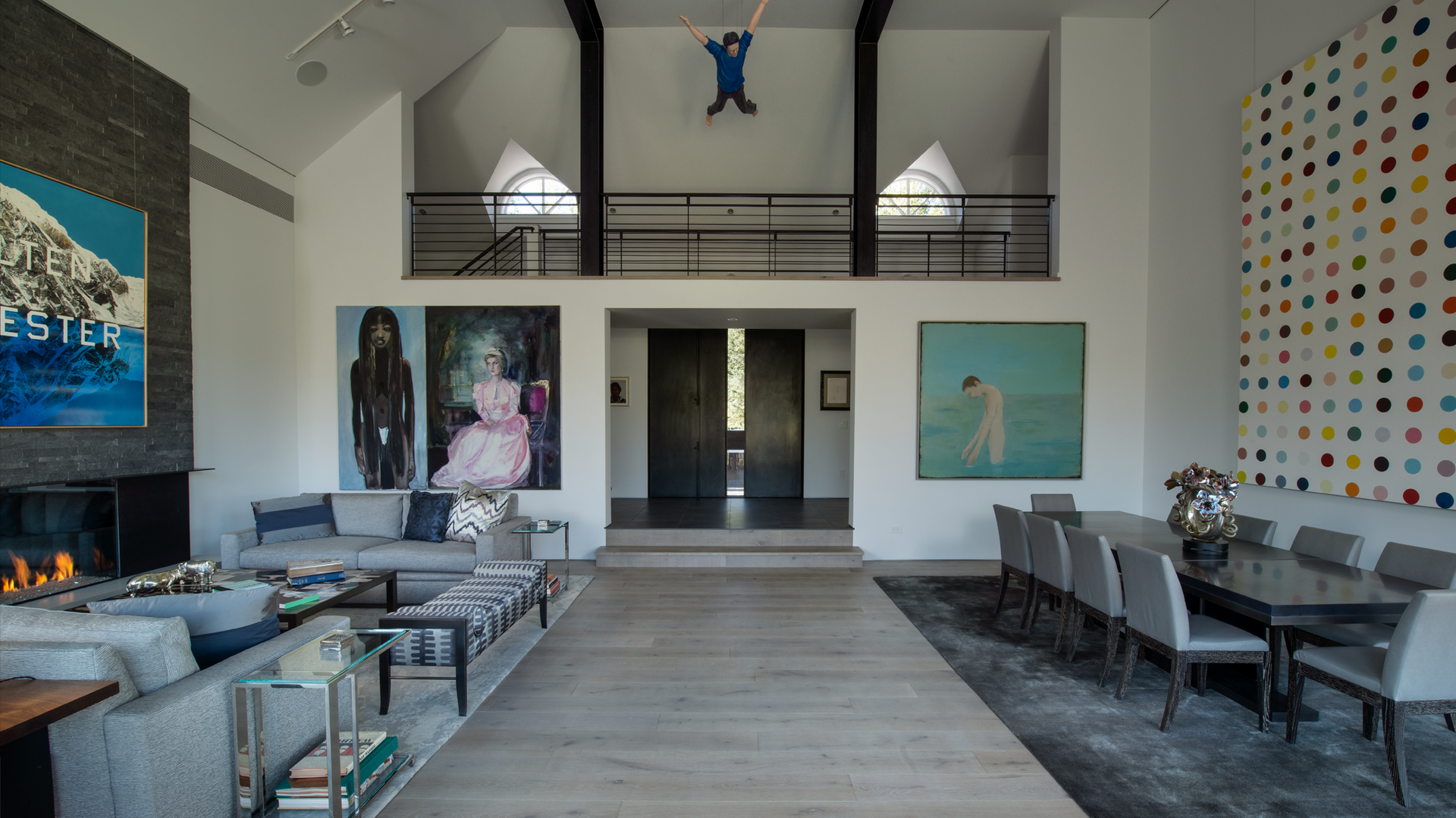 A living room with a couch , table , chairs and paintings on the wall.