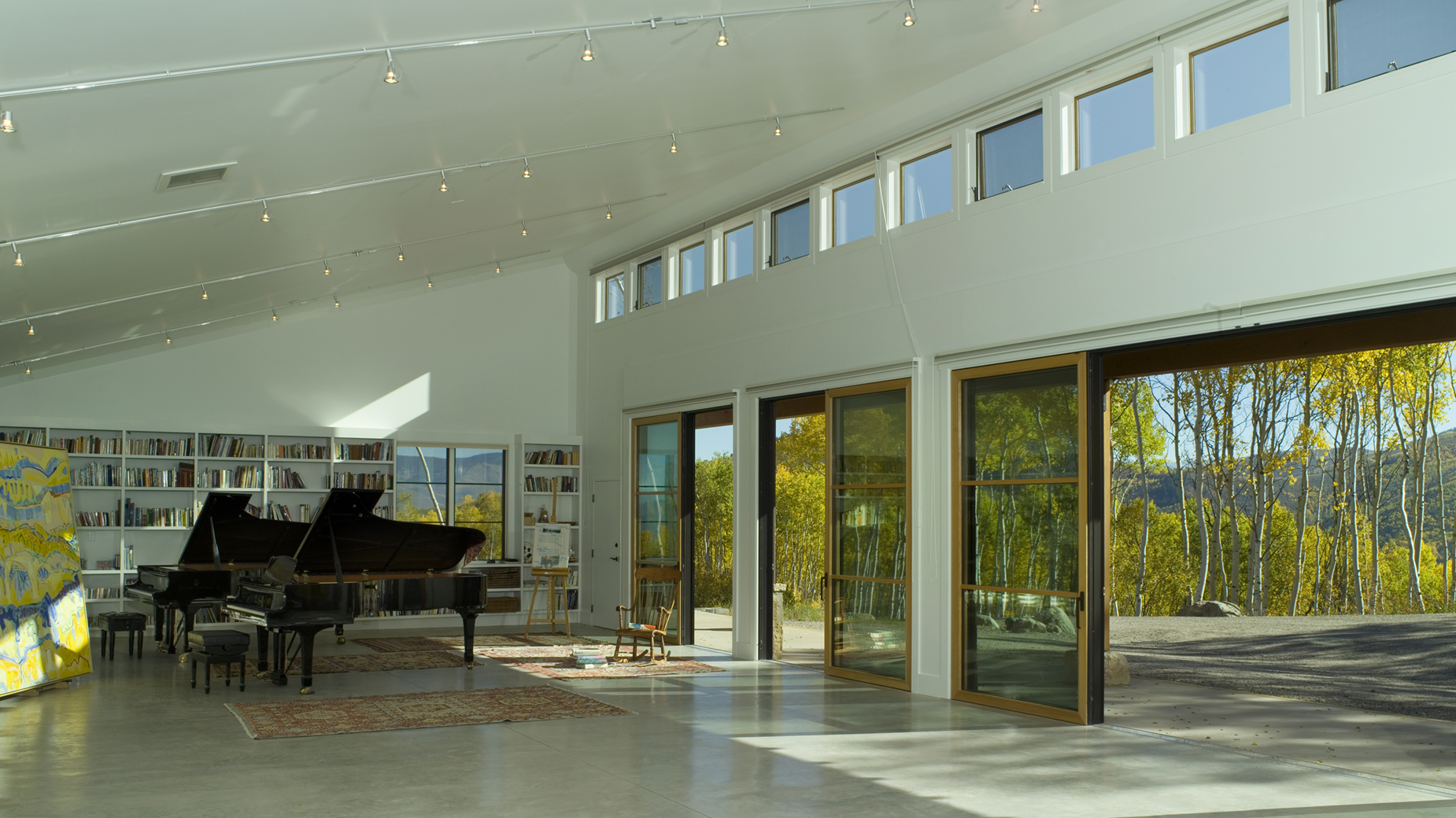 A living room with a piano and a lot of windows