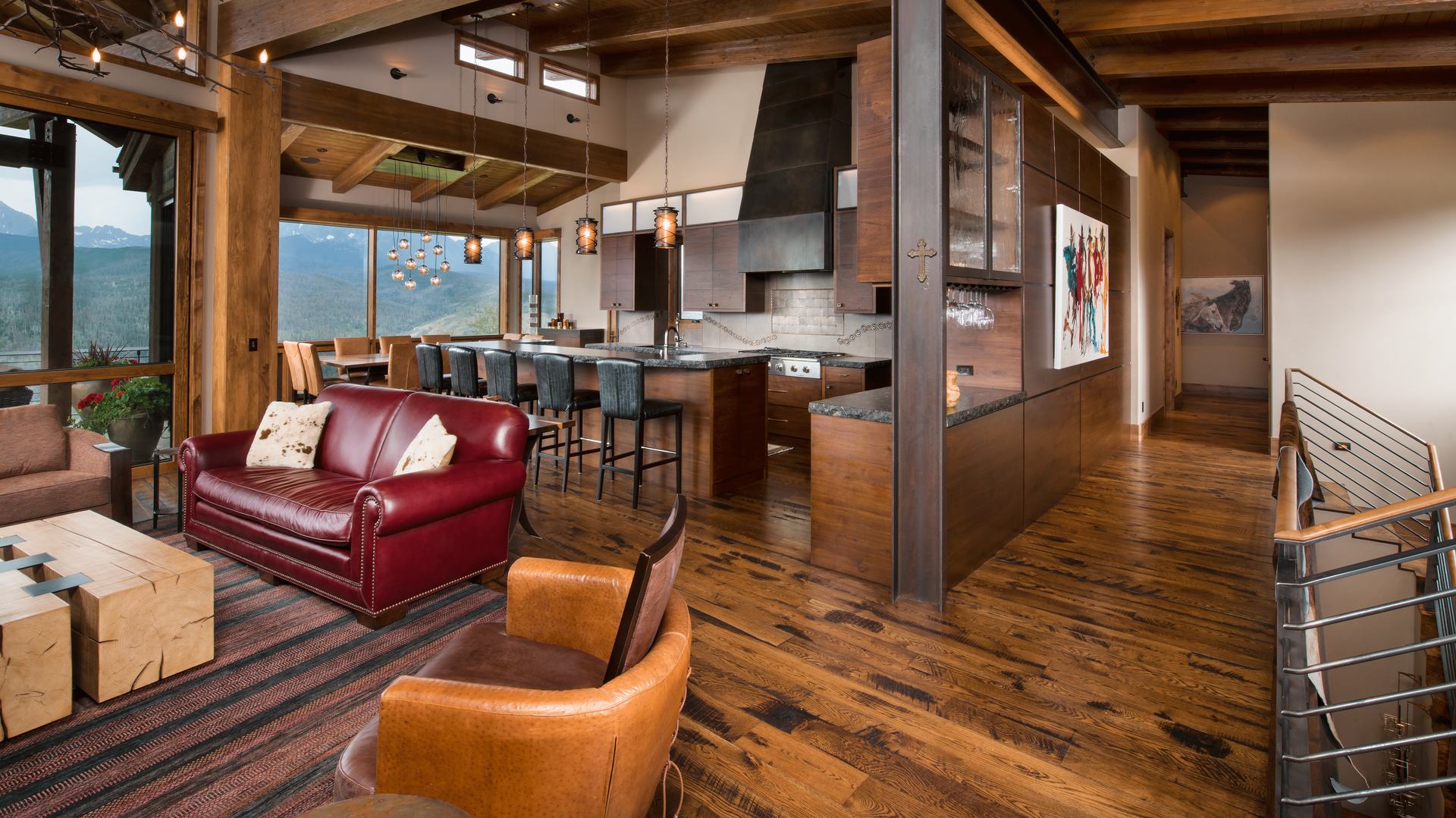 A living room with a red couch and chairs and a kitchen.