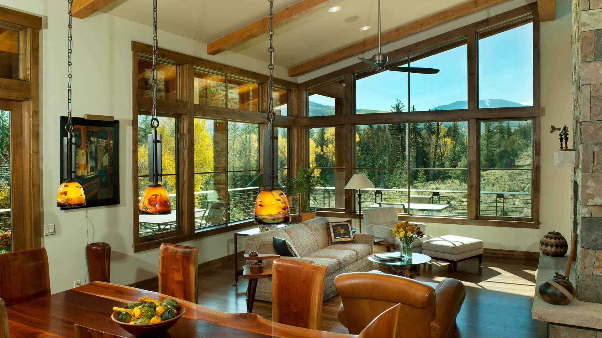 A living room with a lot of windows and a dining table
