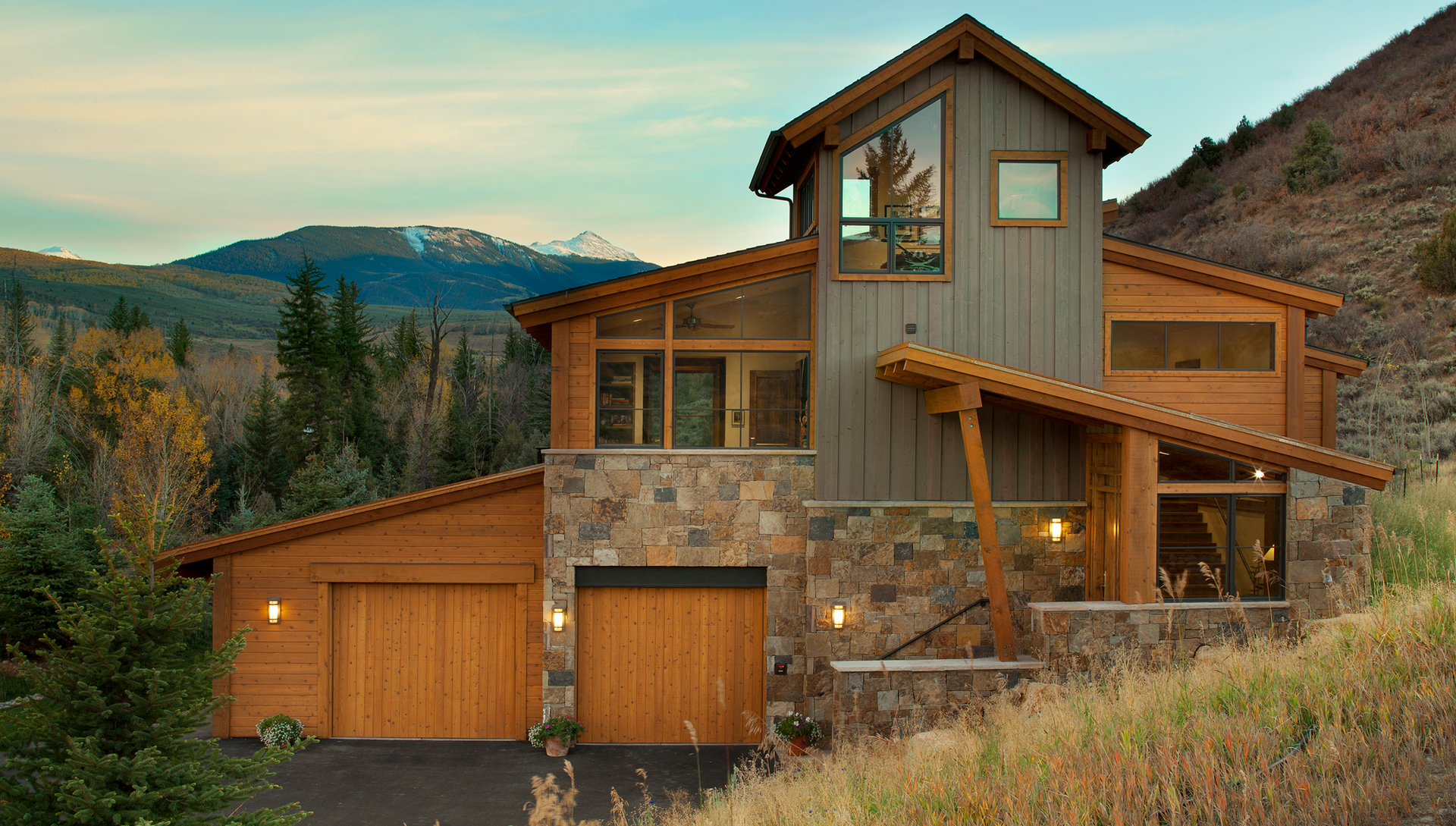 A large house is sitting on top of a hill with mountains in the background.