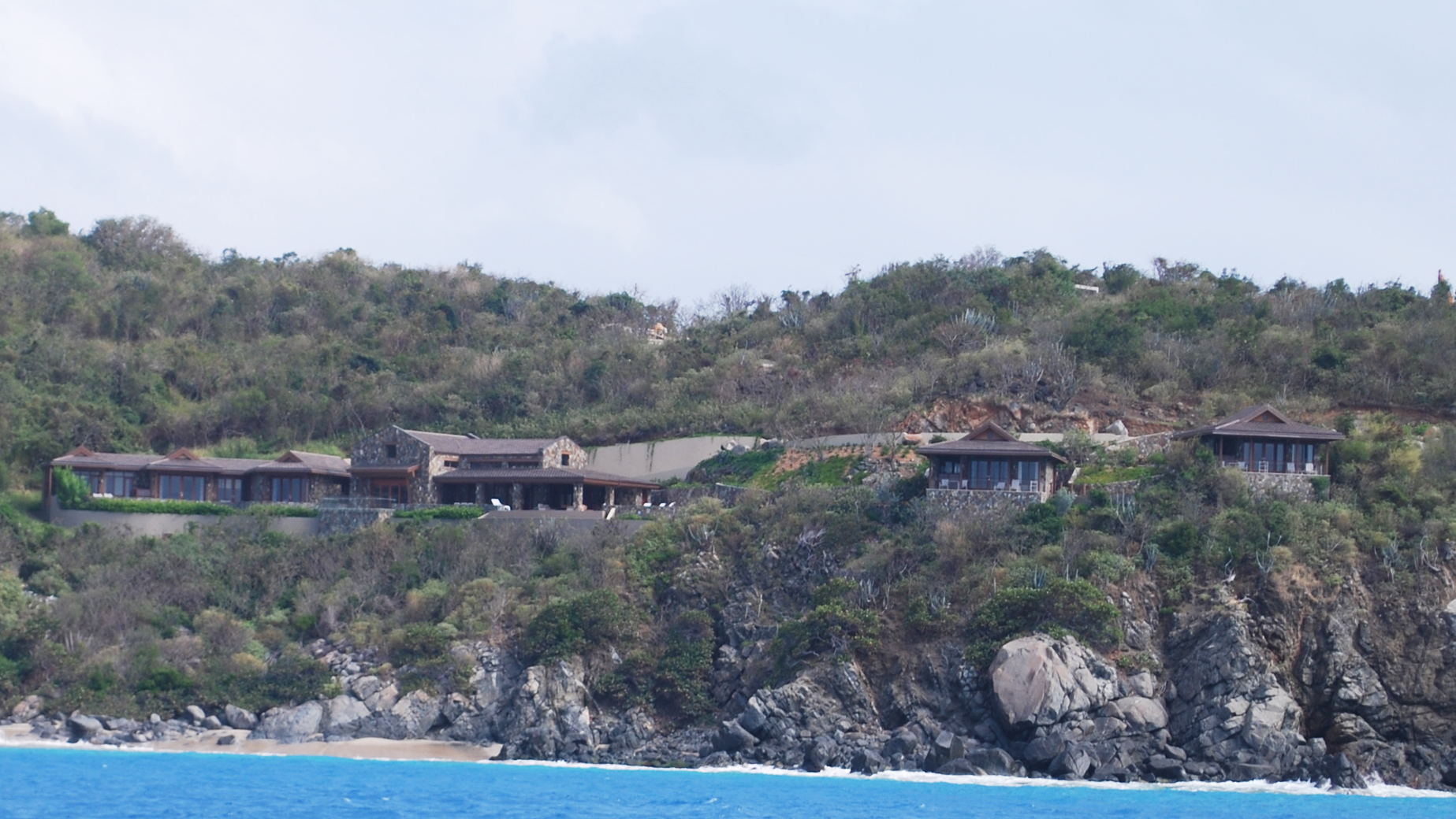 A large house sits on top of a hill overlooking the ocean