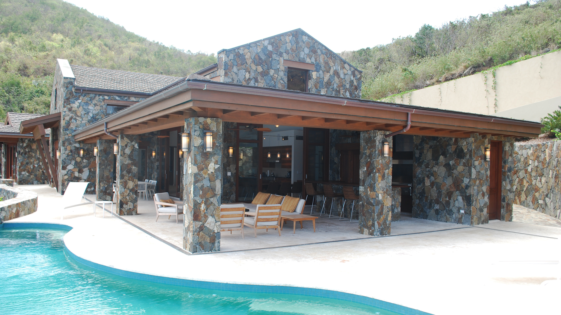 A large stone house with a swimming pool in front of it