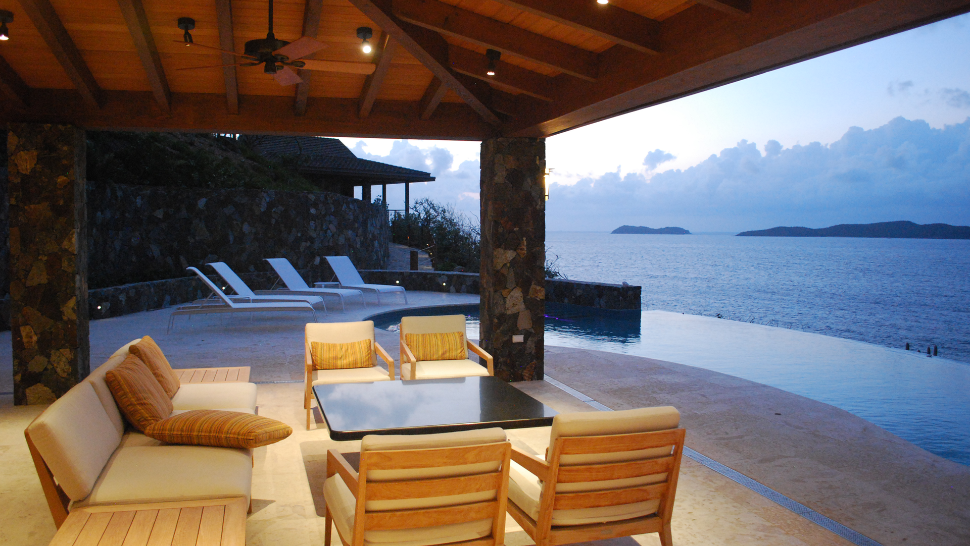 A patio with a couch and chairs overlooking the ocean
