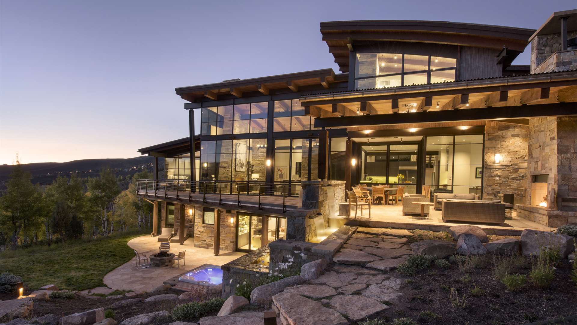 A large house with a lot of windows and a waterfall in front of it.