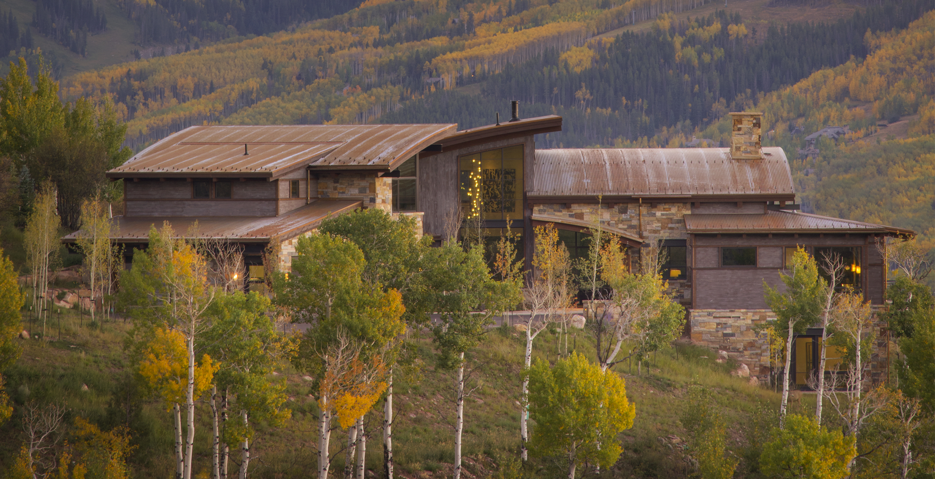 A large house is sitting on top of a hill surrounded by trees.