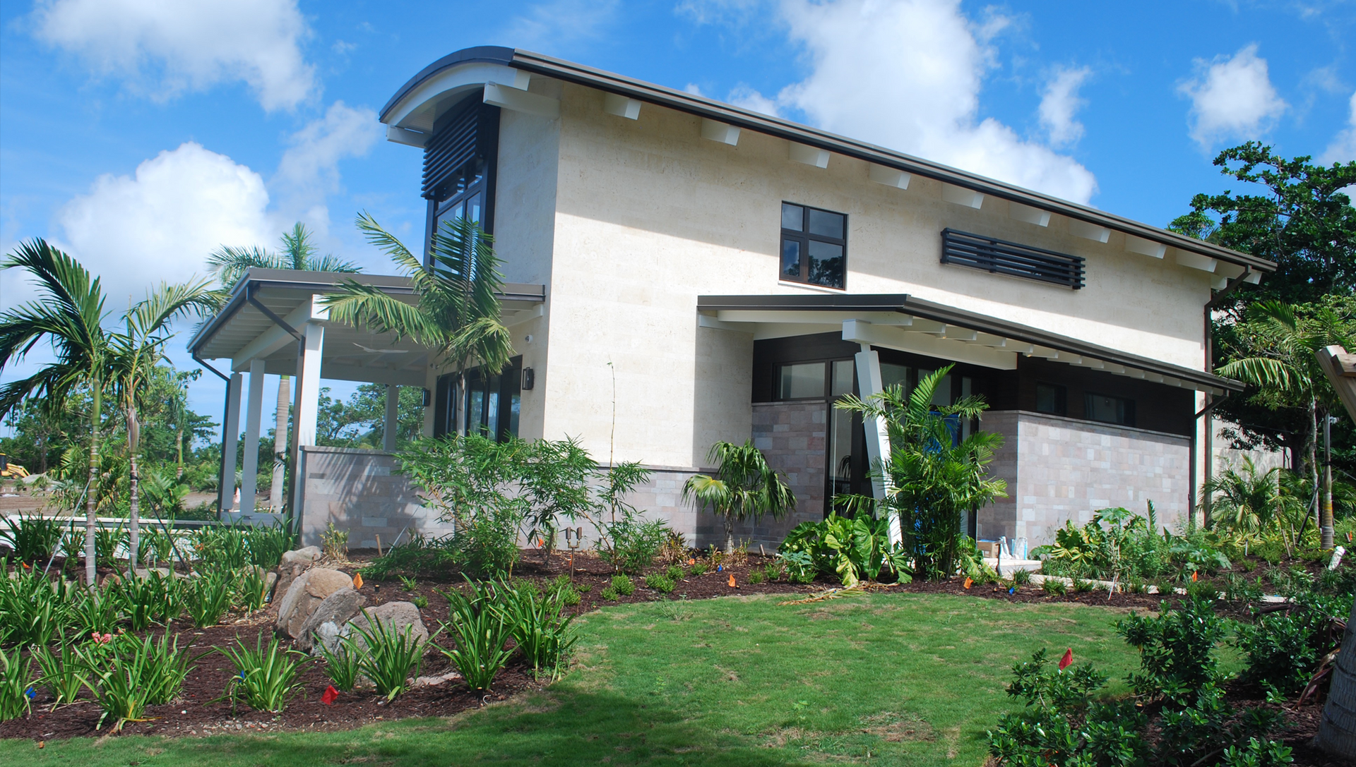 A white house with a curved roof sits in the middle of a lush green field
