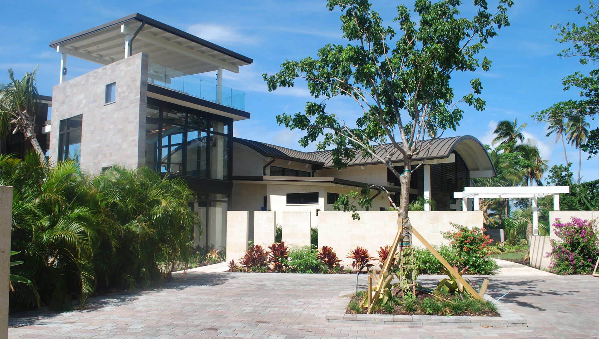 A large house is surrounded by trees and bushes on a sunny day