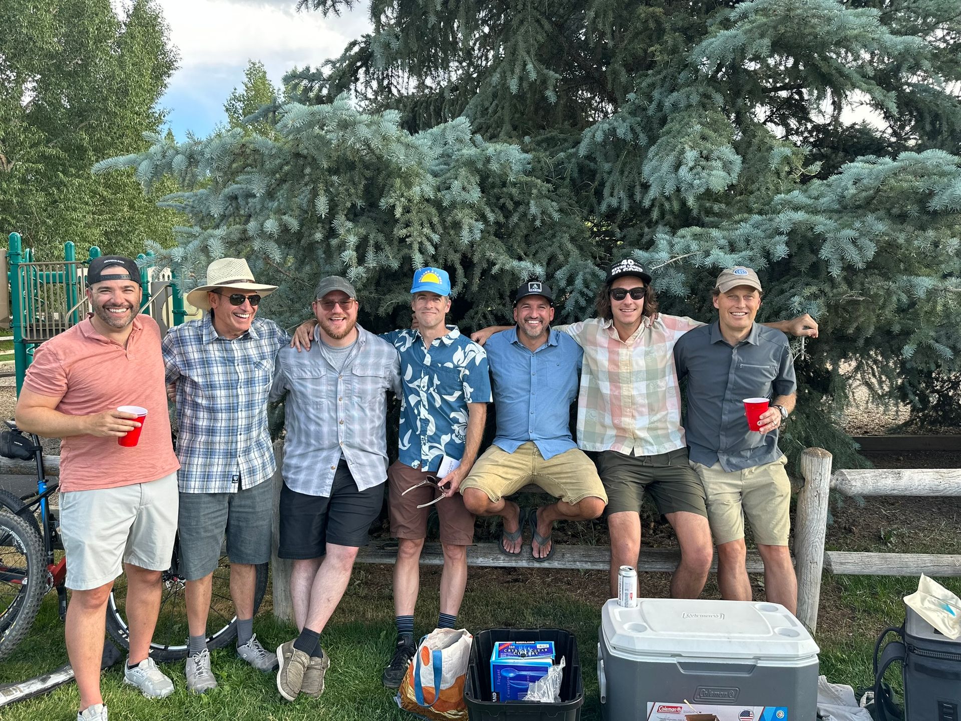 A group of men are sitting on a bench in a park.