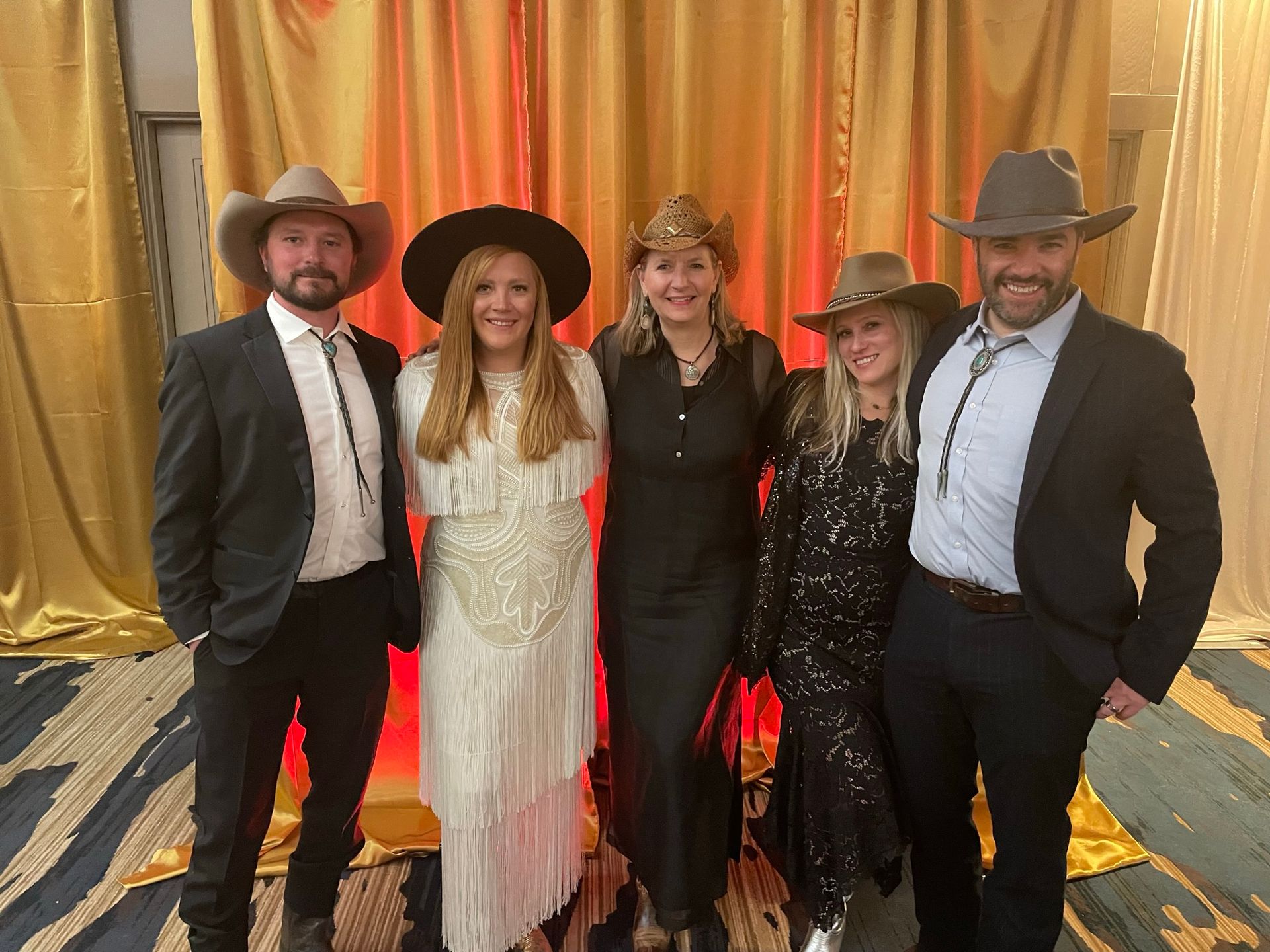 A group of people wearing cowboy hats and dresses are posing for a picture.