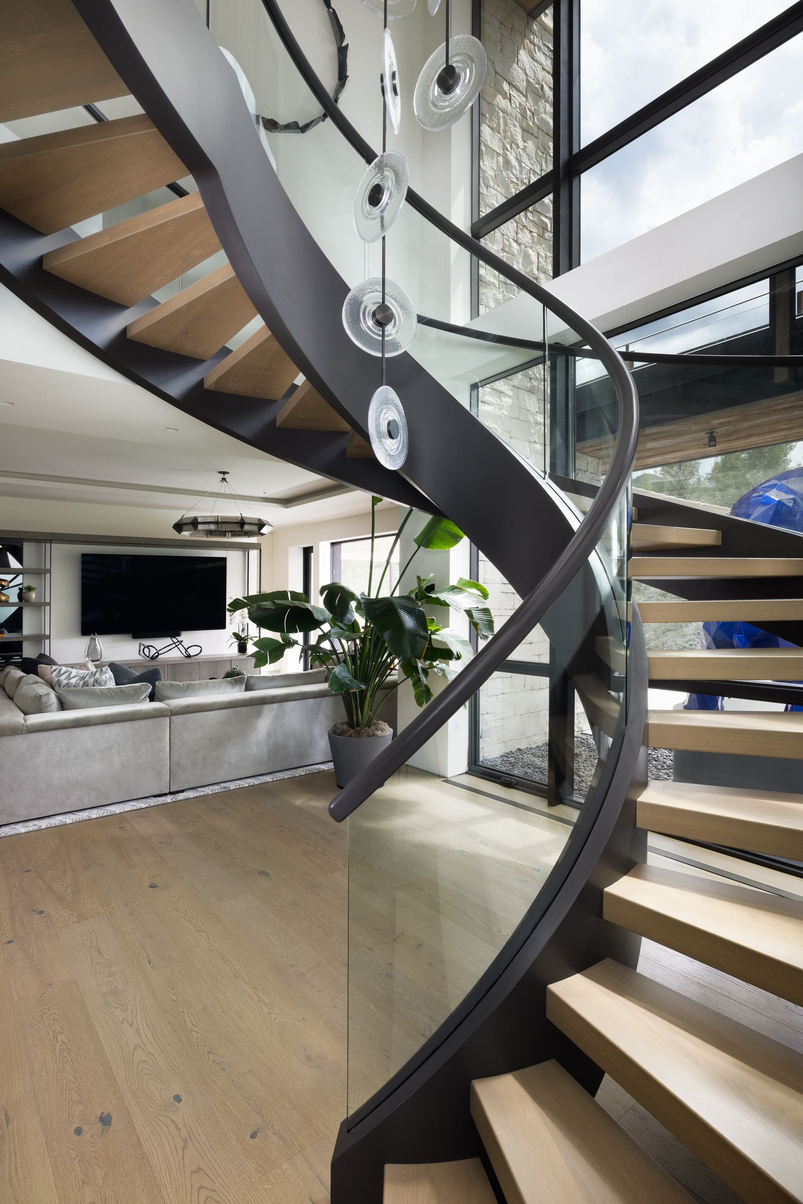 A spiral staircase in a living room with a glass railing