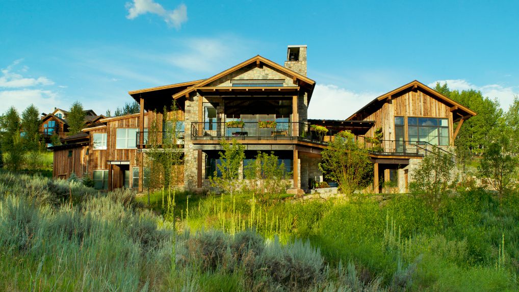 A large house is sitting in the middle of a grassy field.