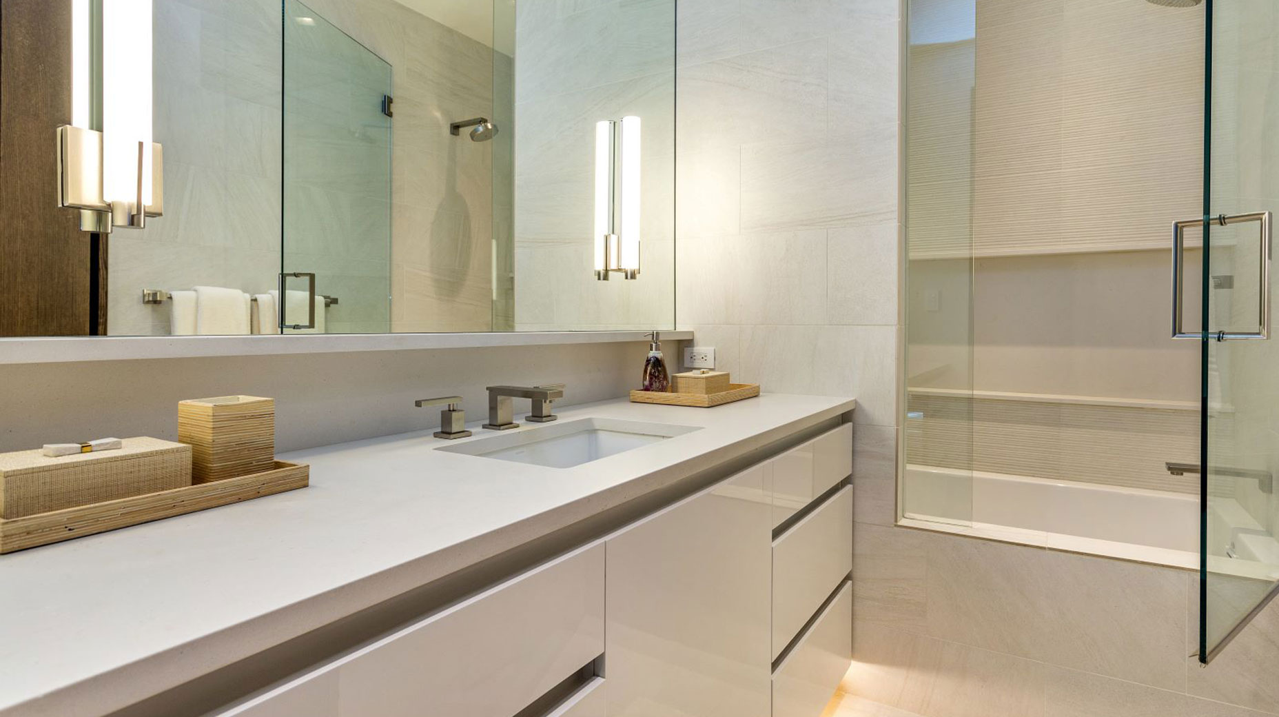 A bathroom with a sink , mirror , tub and shower.