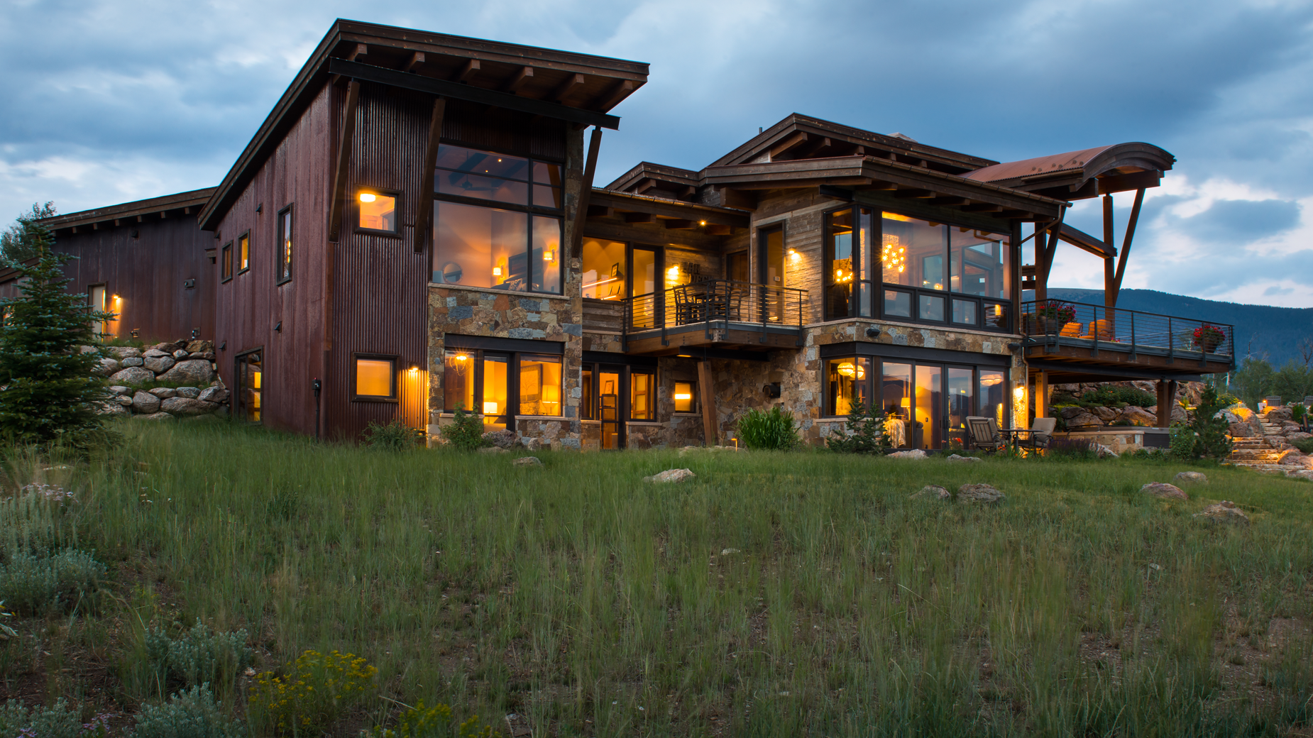 A large house with a lot of windows is sitting in the middle of a grassy field.