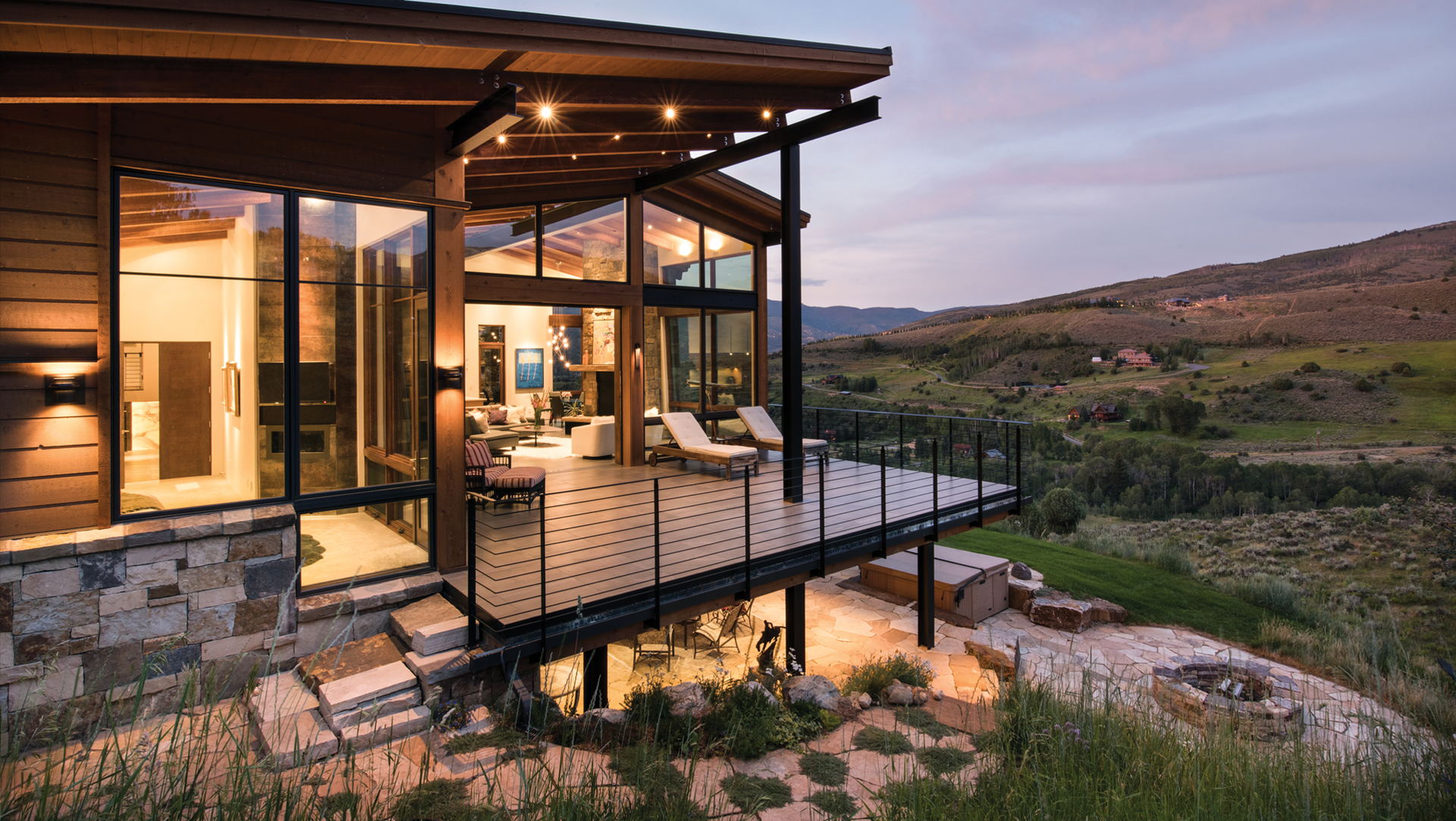 An aerial view of a house in the mountains with a play button.