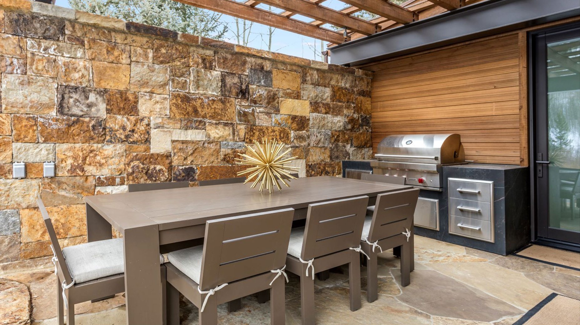 A patio with a table and chairs and a grill.