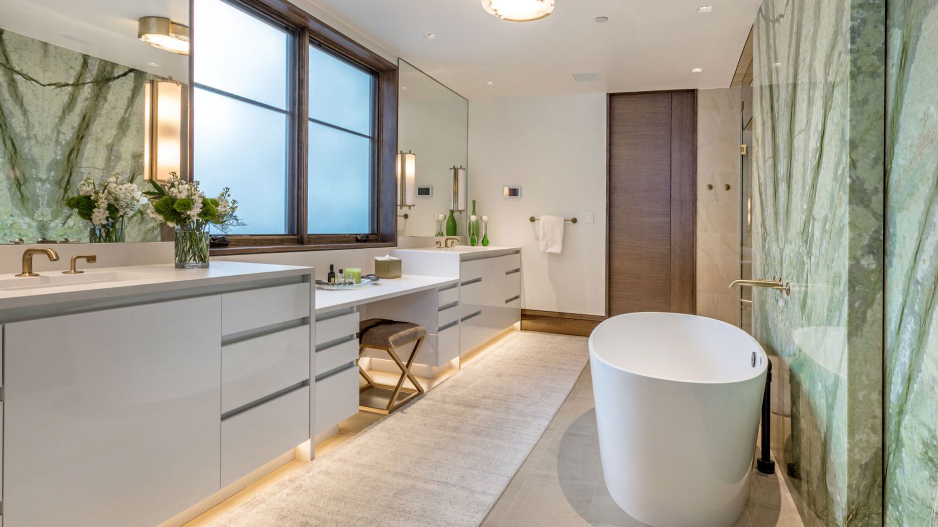 A bathroom with a tub , sink , mirror and window.
