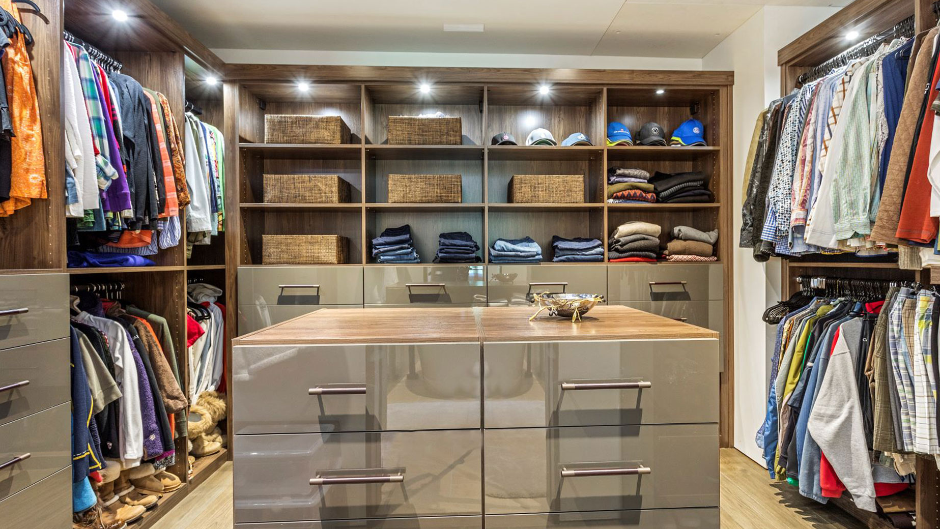 A walk in closet filled with lots of clothes and drawers.