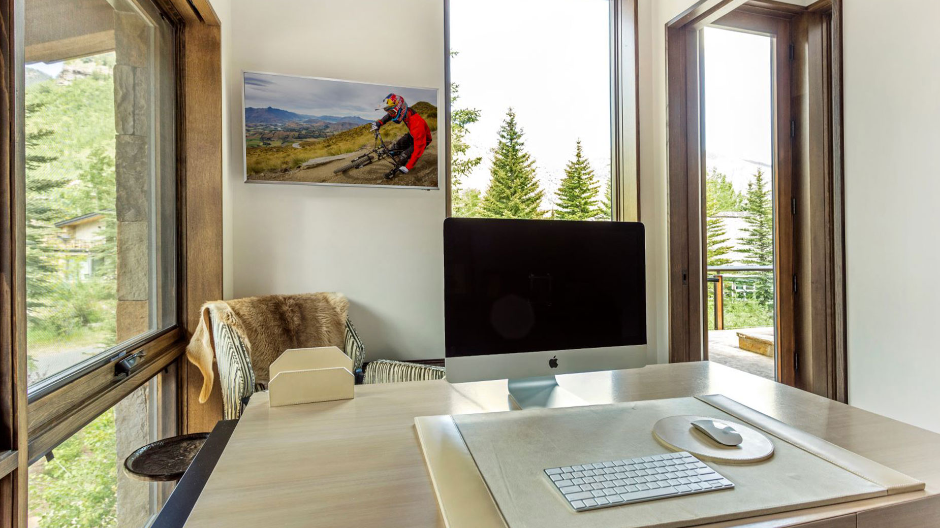 A desk with a computer on it in a room with a large window.