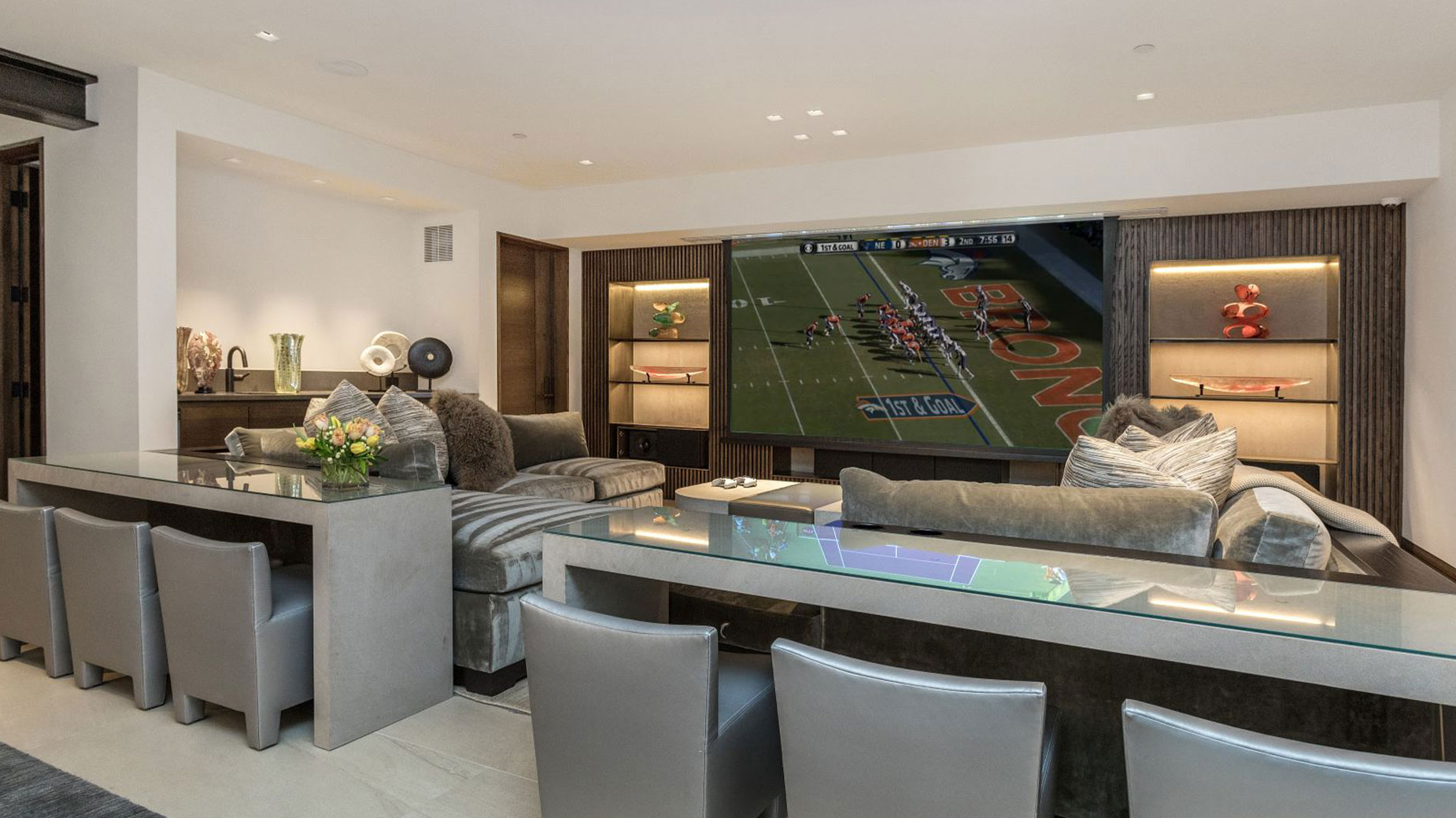 A living room with a large flat screen tv and a bar.