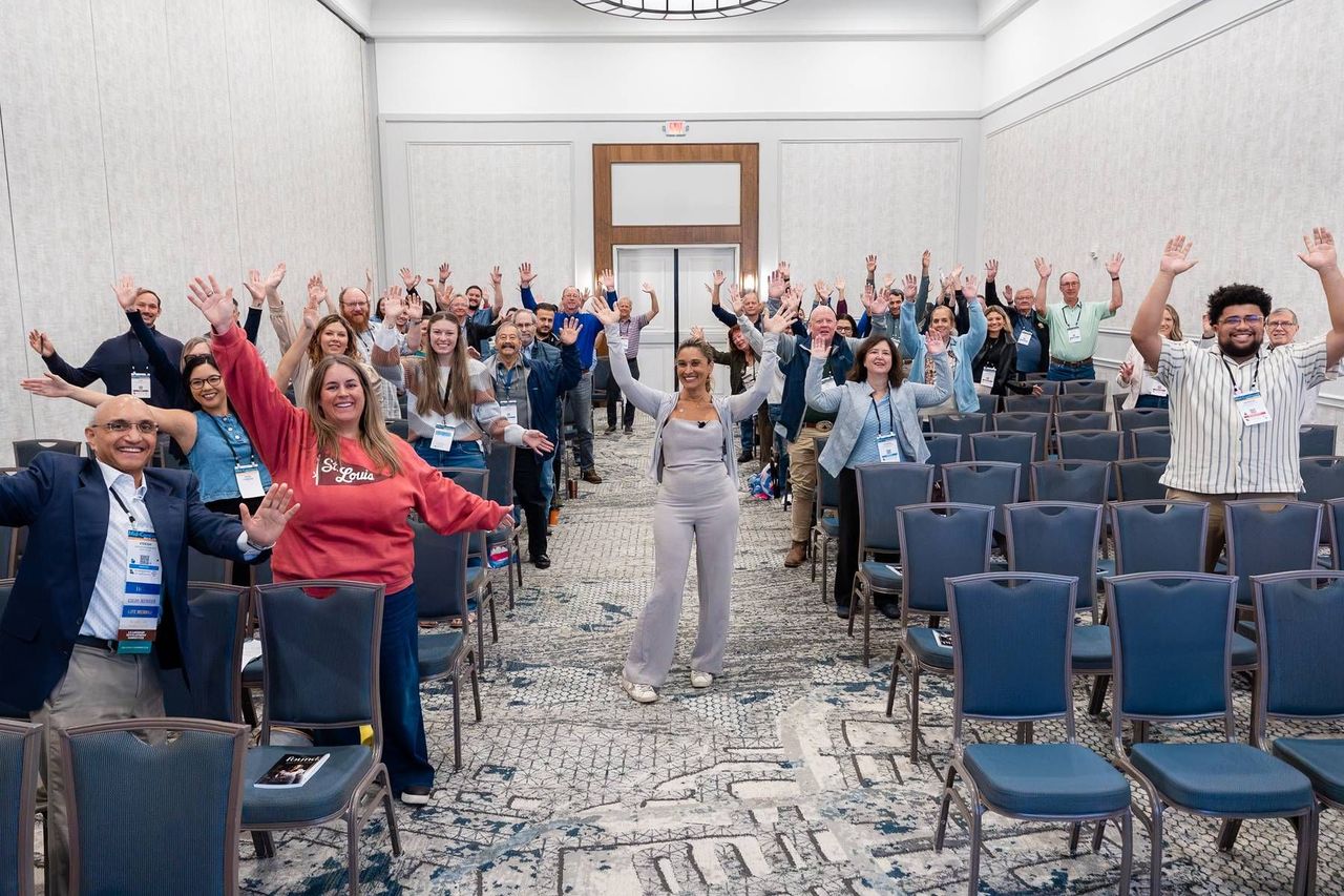 Dr. Anissa Broussard and a full classroom with their arms raised at the Mid-Continent Dental Congress