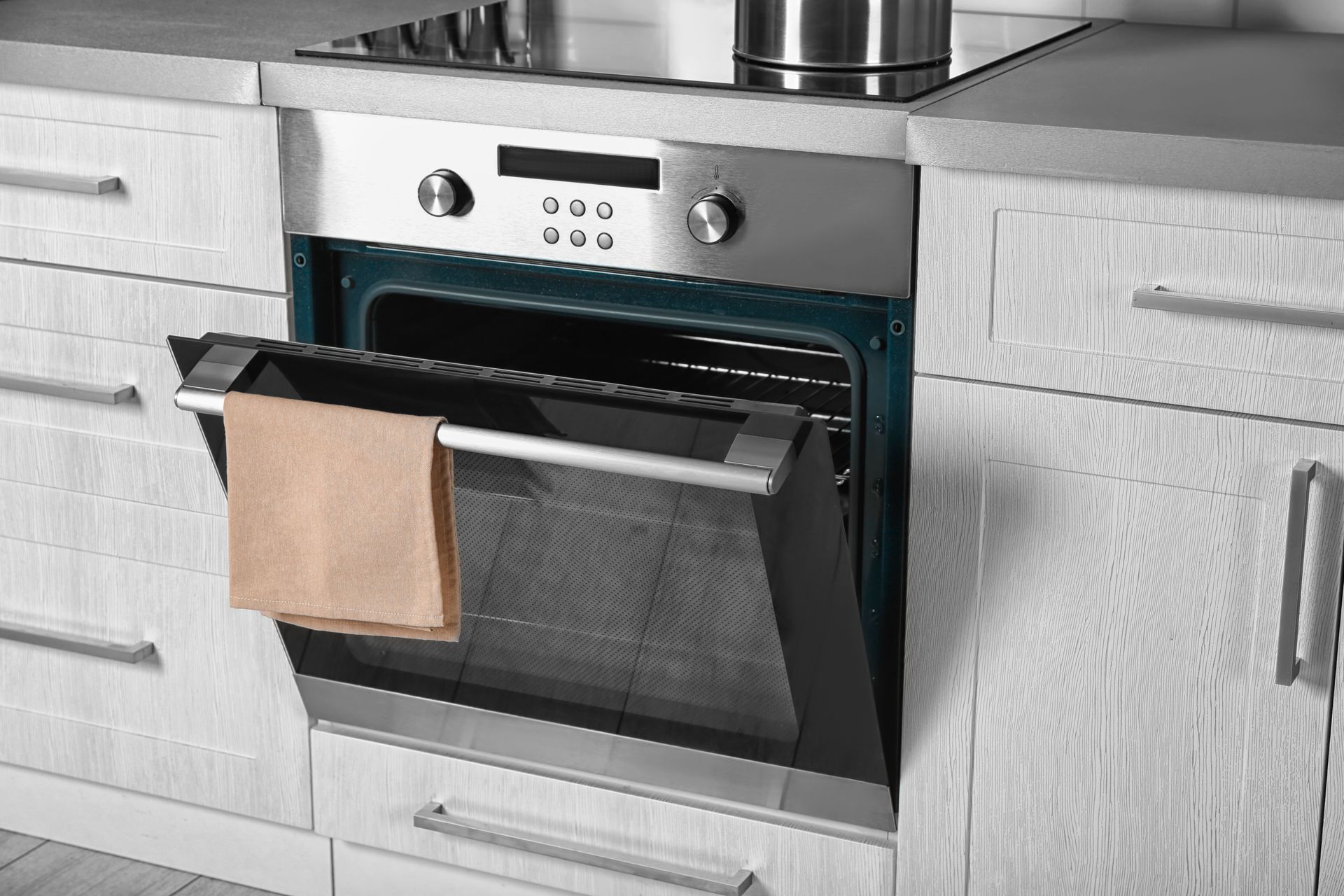 Built-in oven with a hanging towel in a modern kitchen cabinet countertop setting