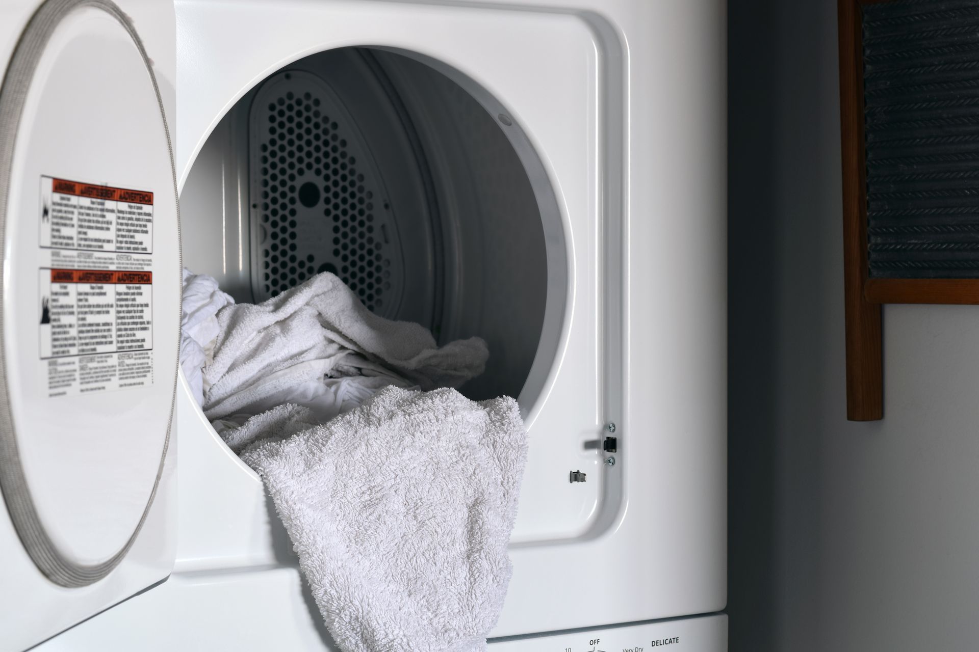White laundry spilling from an open dryer door in a laundry room.