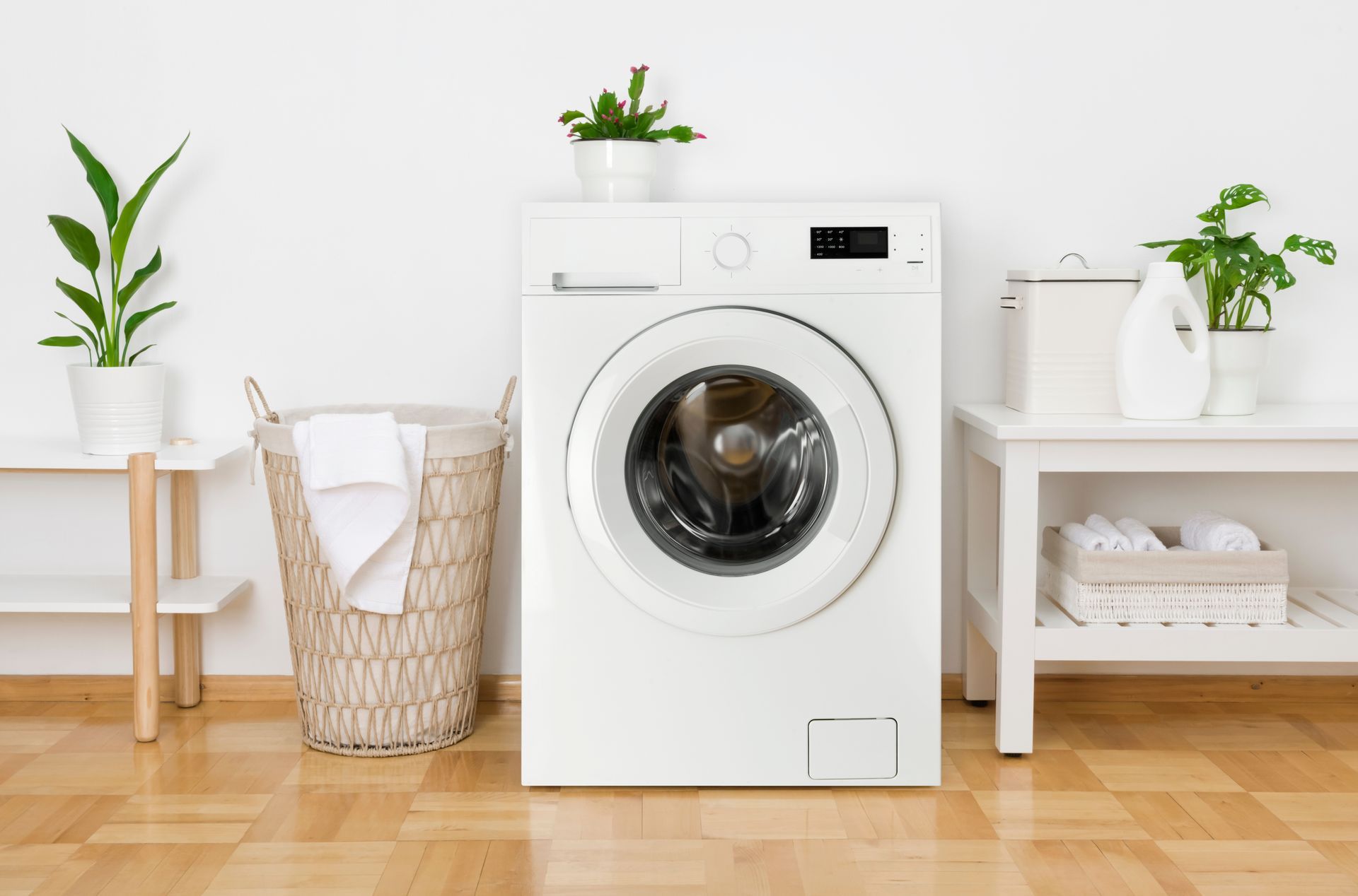 Bright laundry room with front-load washer, wicker hamper, and potted plants on white shelves