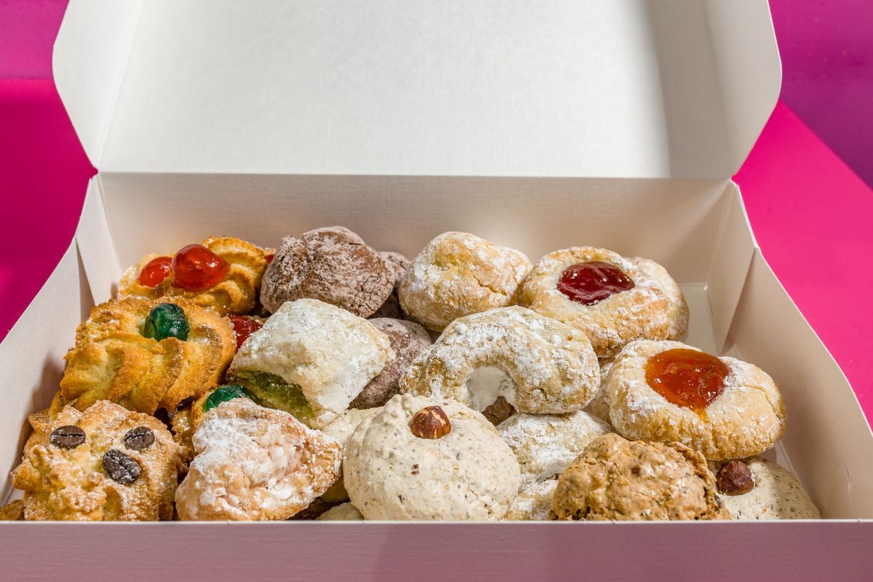 Scatola di ciambelle e pasticcini assortiti ricoperti di zucchero a velo con ripieni di gelatina e glassa colorata.