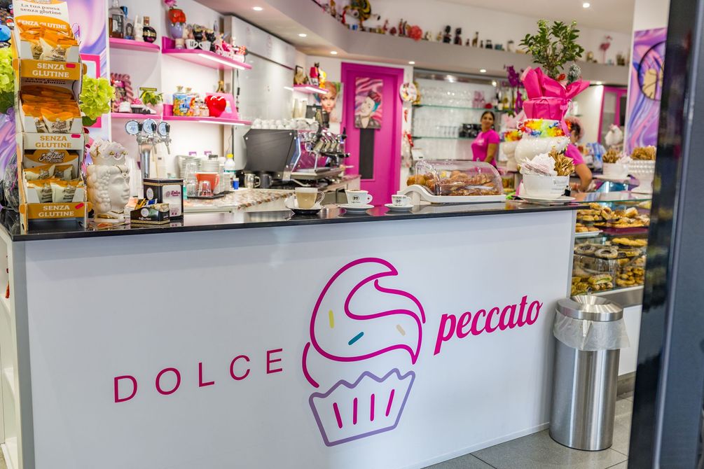 Bancone dei dolci rosa e bianco con vetrine e insegna 