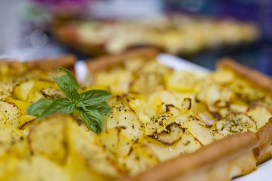Primo piano di una sfoglia dorata cotta al forno con guarnizione di erbe aromatiche su un vassoio.