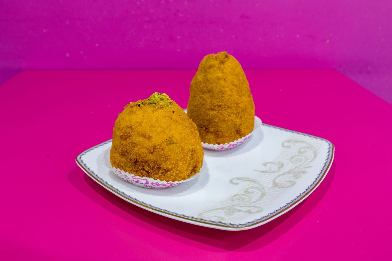 Due snack fritti arancioni su un piatto decorativo bianco su uno sfondo rosa acceso